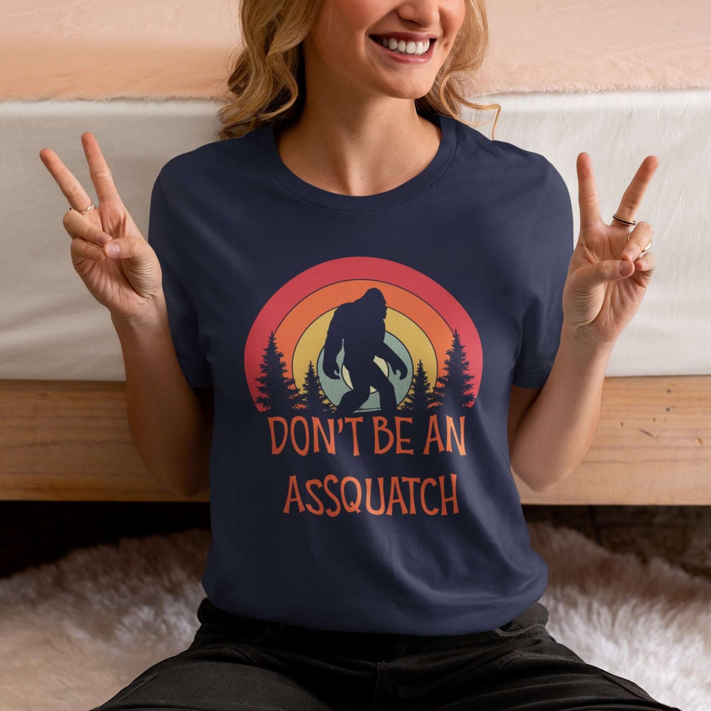 Woman wearing navy blue t-shirt with sasquatch graphic and the words don't be an assquatch printed on the front.