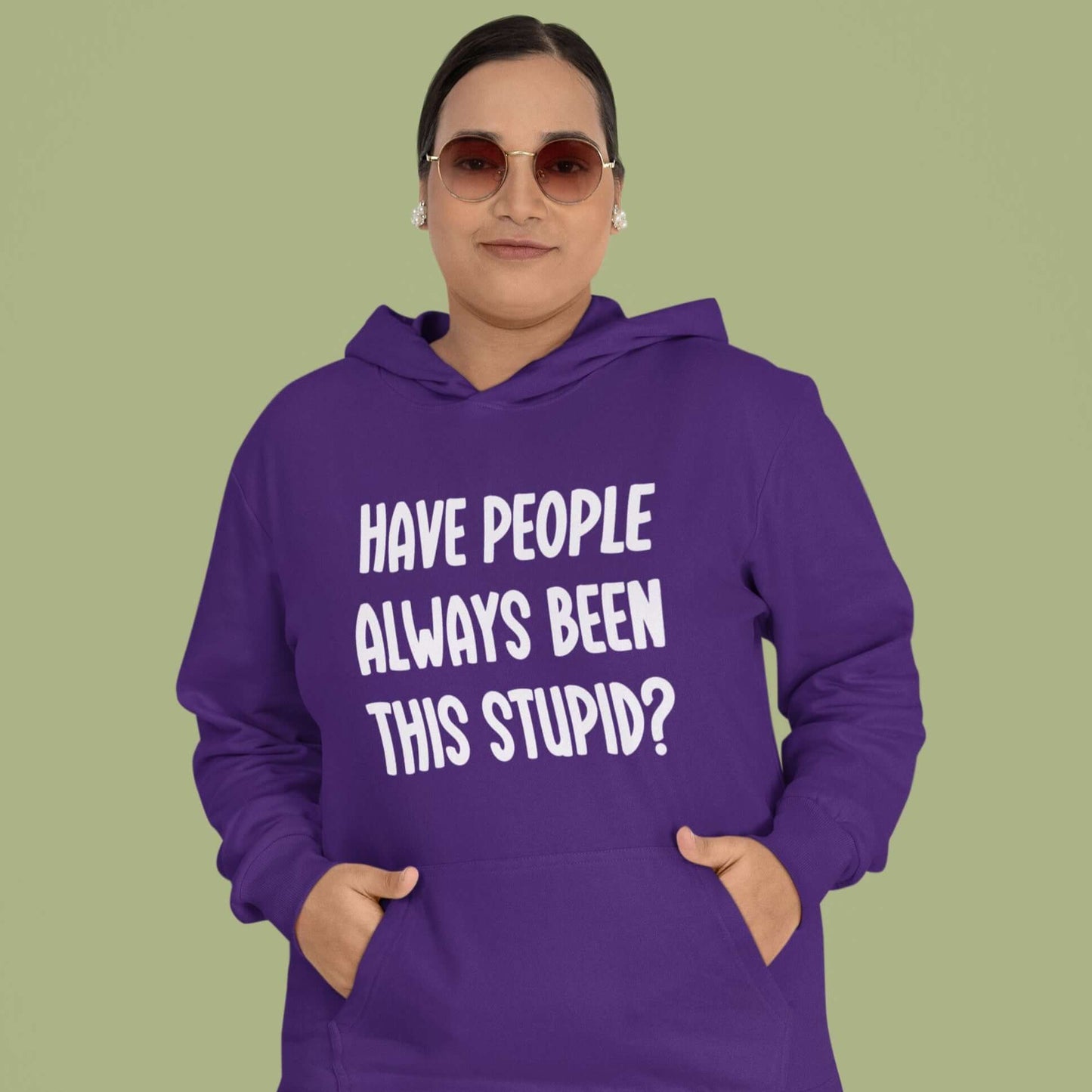 Woman wearing a purple hoodie sweatshirt with the question Have people always been this stupid question mark printed on the front.