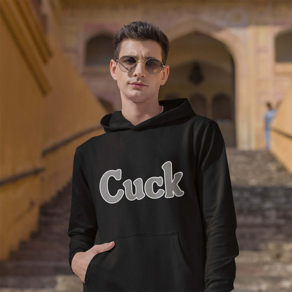 Man wearing sunglasses and a black hoodie sweatshirt with the word Cuck printed on the front in grey.