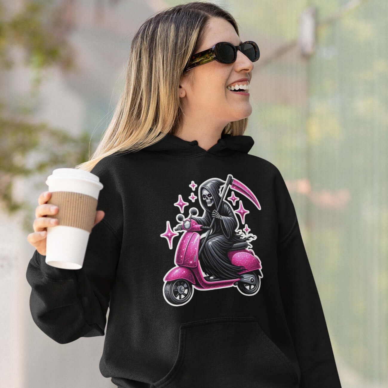 Woman wearing a black hoodie sweatshirt with funny image of the Grim Reaper riding on a glam pink scooter printed on the front.