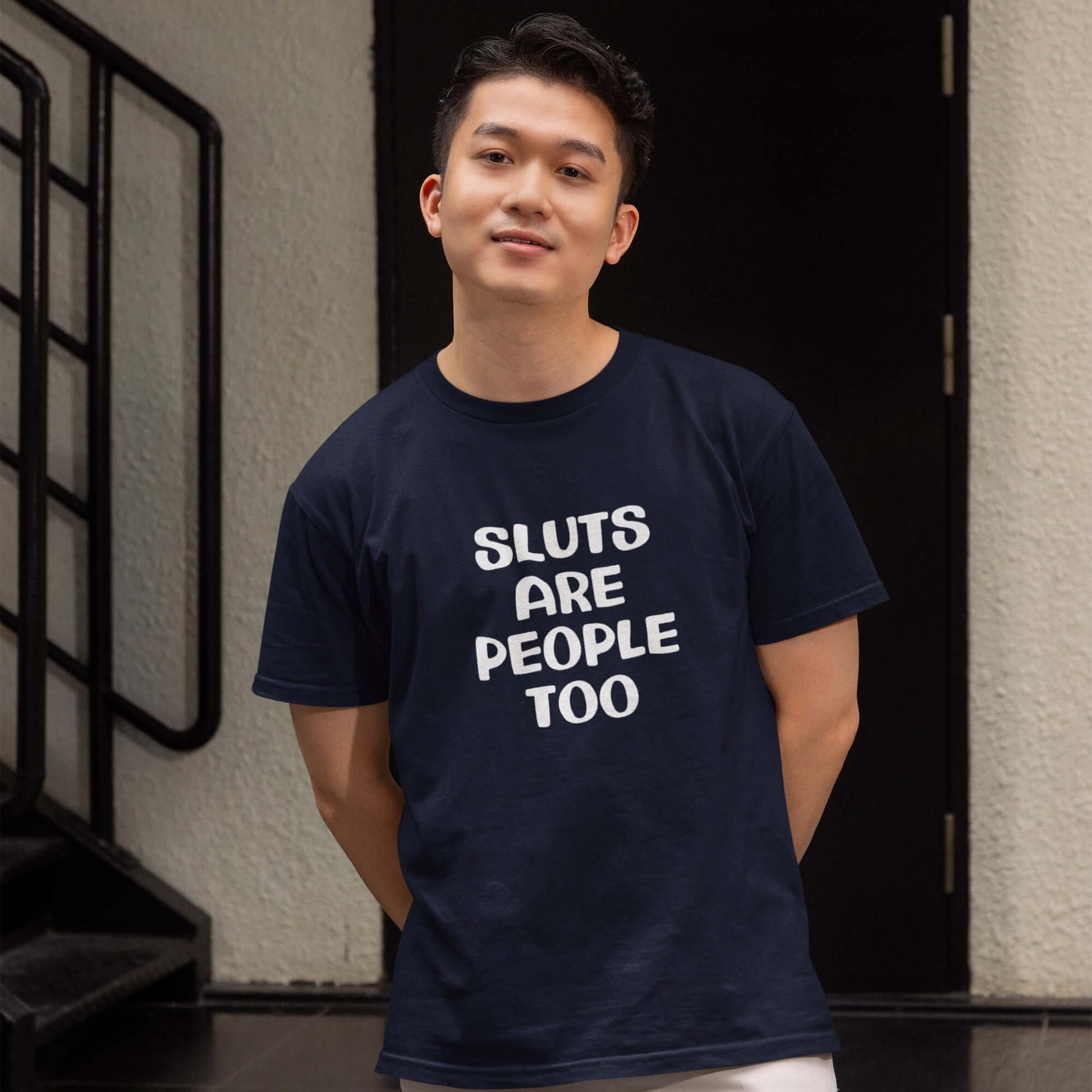 Man wearing a navy blue t-shirt with the phrase Sluts are people too printed on the front.