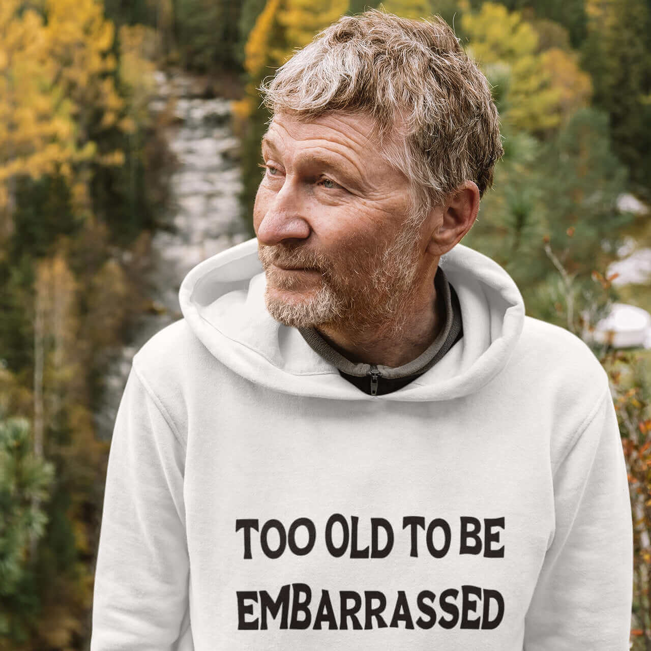 Older gentleman wearing a white hooded sweatshirt with the words Too old to be embarrassed printed on the front.