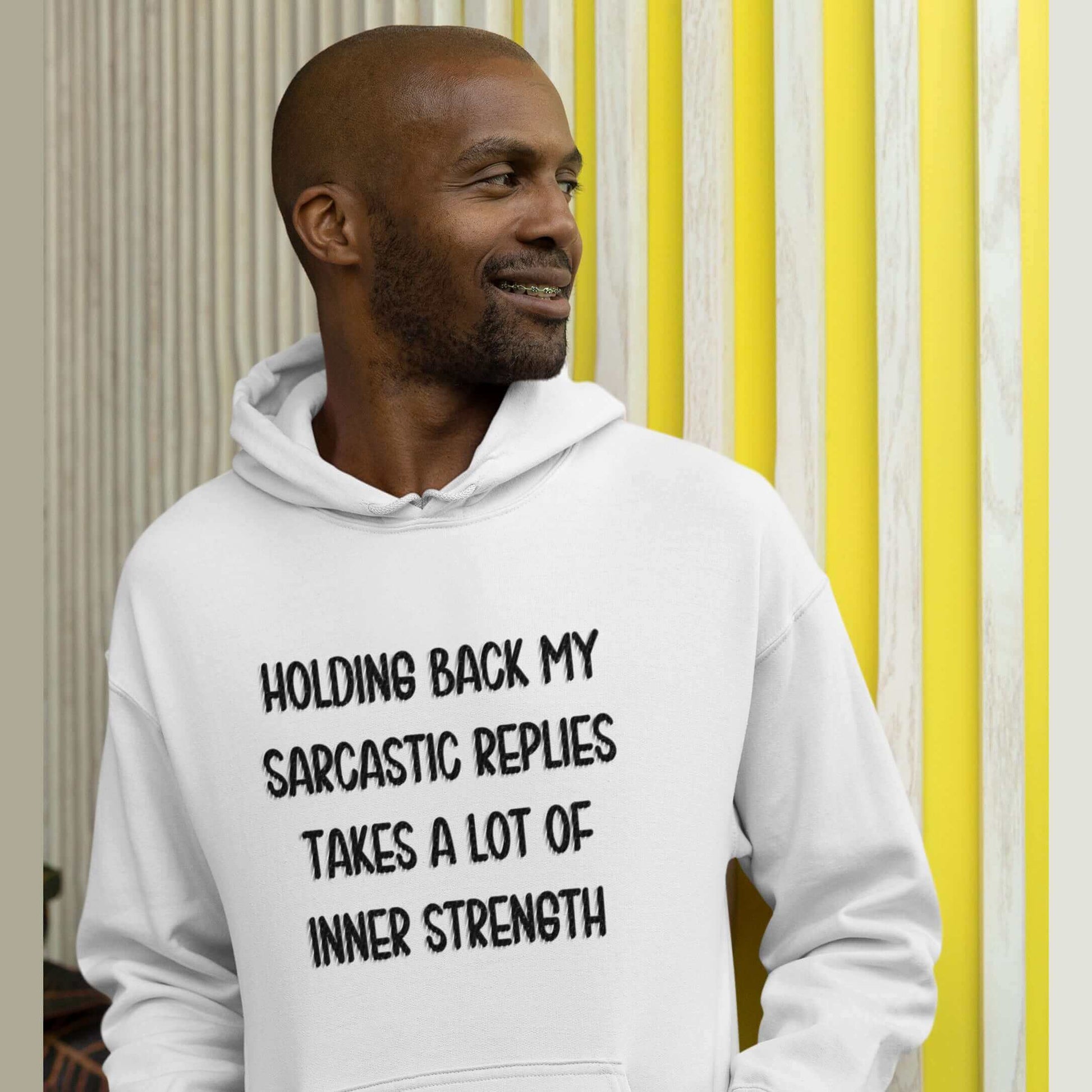 Man wearing white hoodie sweatshirt with the phrase Holding back my sarcastic replies takes a lot of inner strength printed on the front.