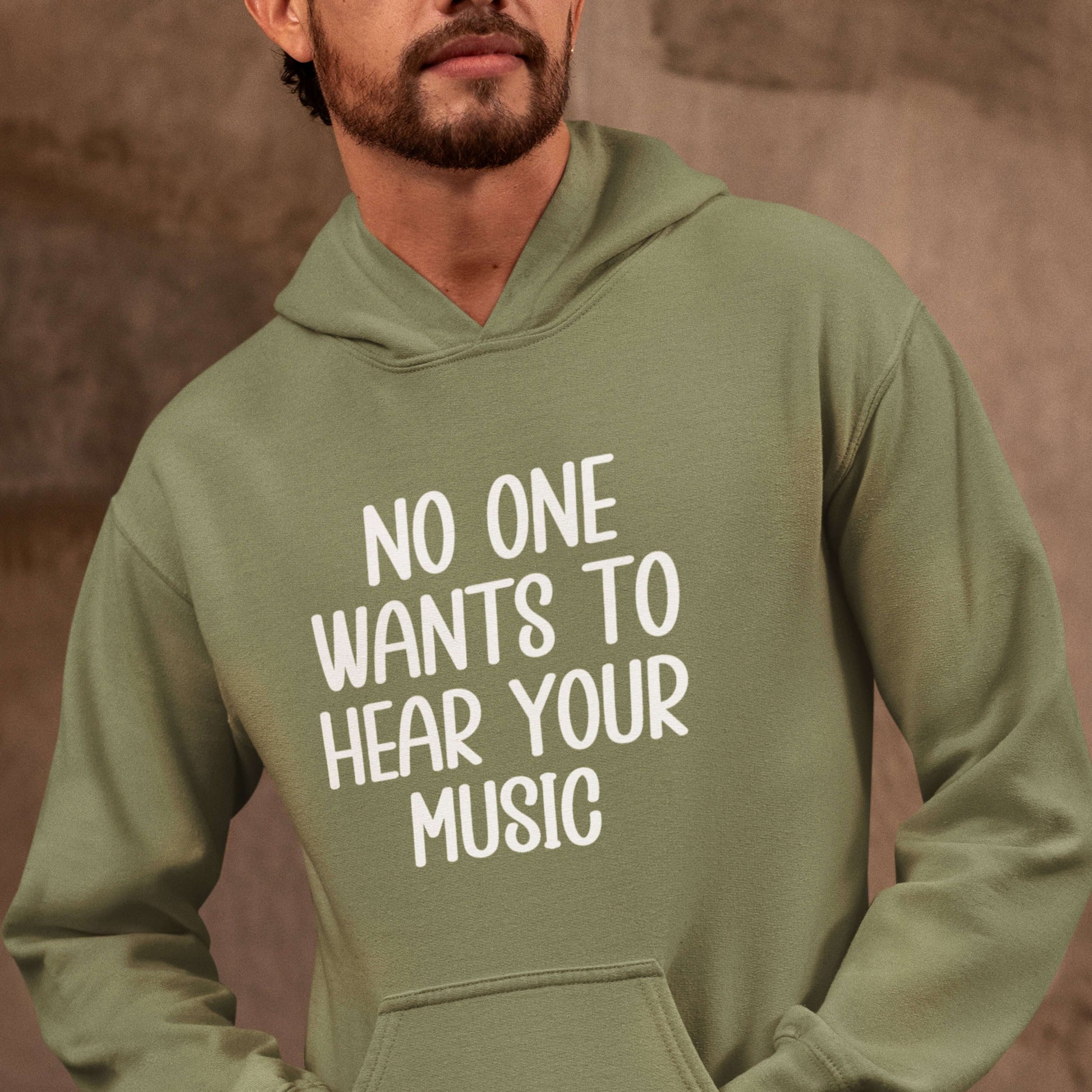 Man wearing a military green hoodie sweatshirt that has the phrase No one wants to hear your music printed on the front.