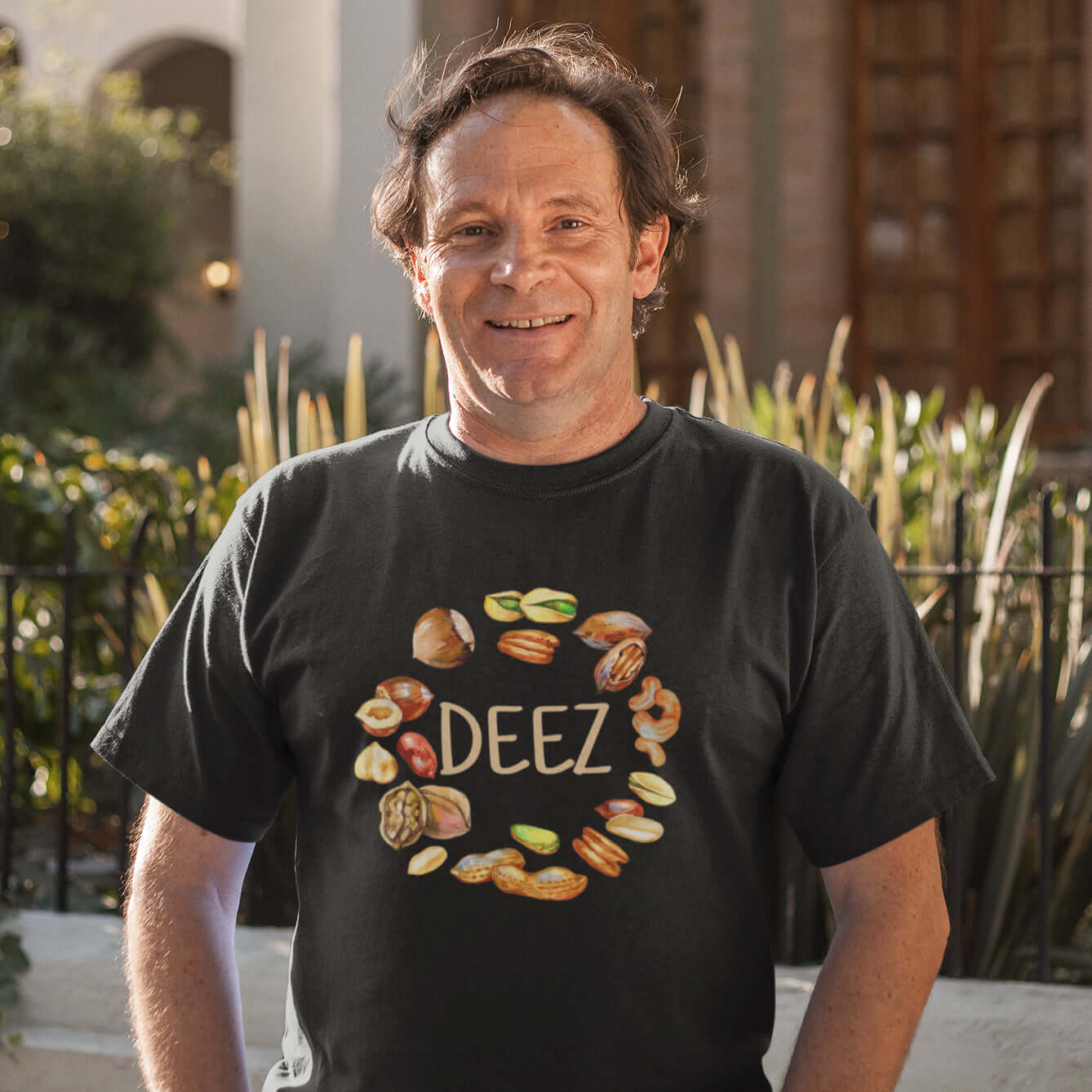 Man wearing a black t-shirt with an image of various nuts and the word Deez printed on the front.,