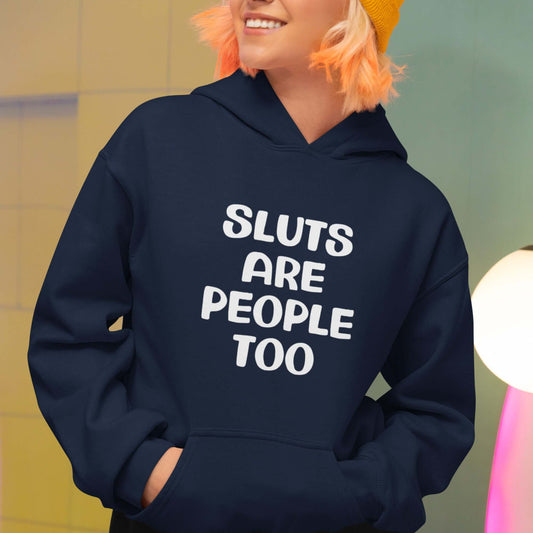 Woman wearing a navy blue hoodie sweatshirt with the phrase Sluts are people too printed on the front.