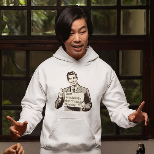 Man wearing a white hoodie sweatshirt with a graphic of a retro man holding a sign. The sign says Ladies, mansplaining is short for man explaining. The graphics are printed on the front of the hoodie.