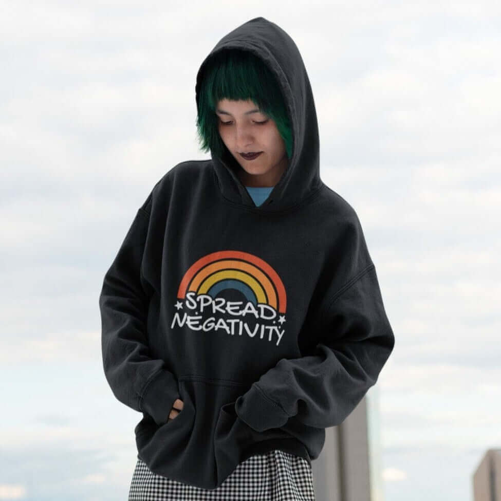 Woman wearing a black hoodie sweatshirt with a graphic of a rainbow and the words Spread negativity printed on the front.