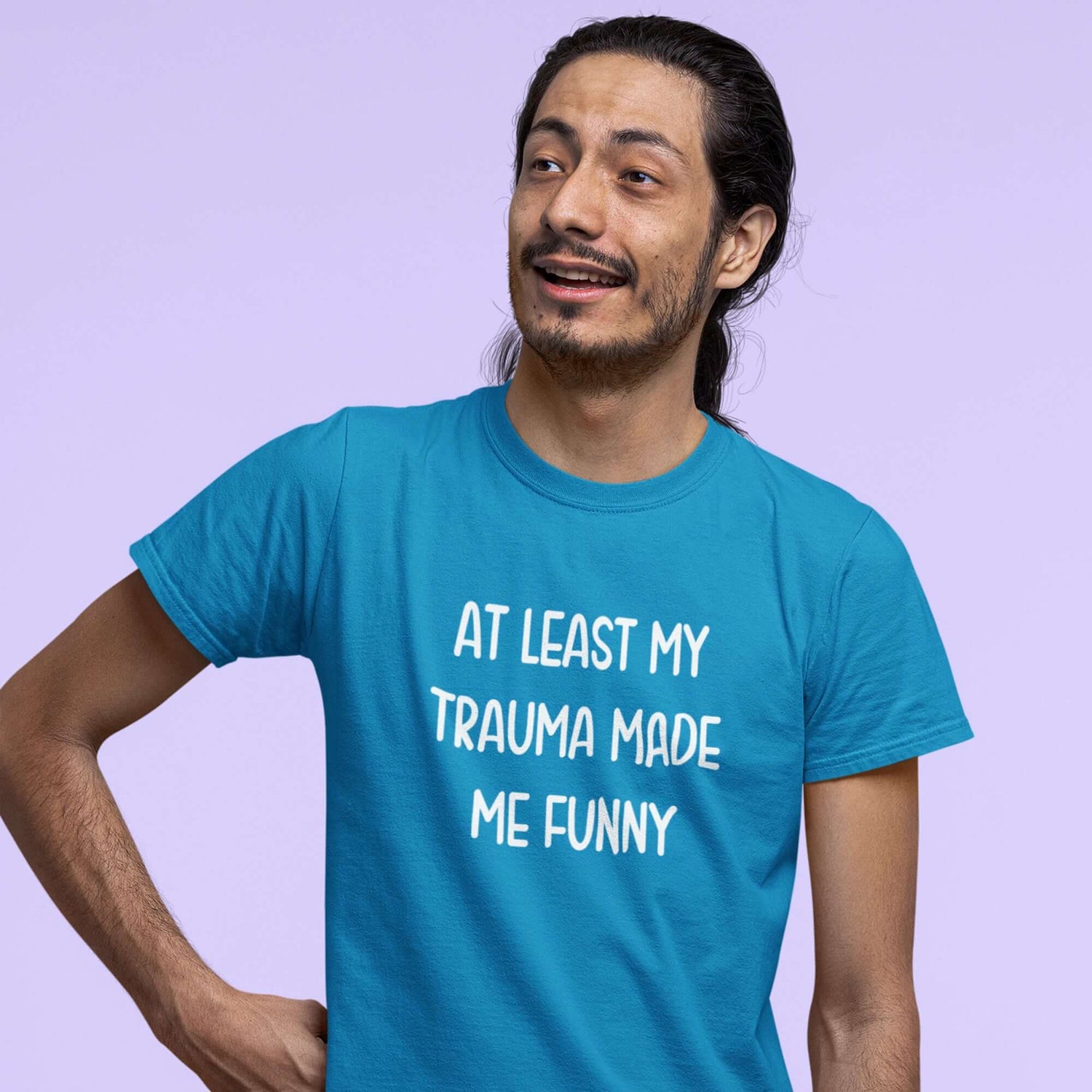 Man wearing a sapphire blue t-shirt with the words At least my trauma made me funny printed on the front.