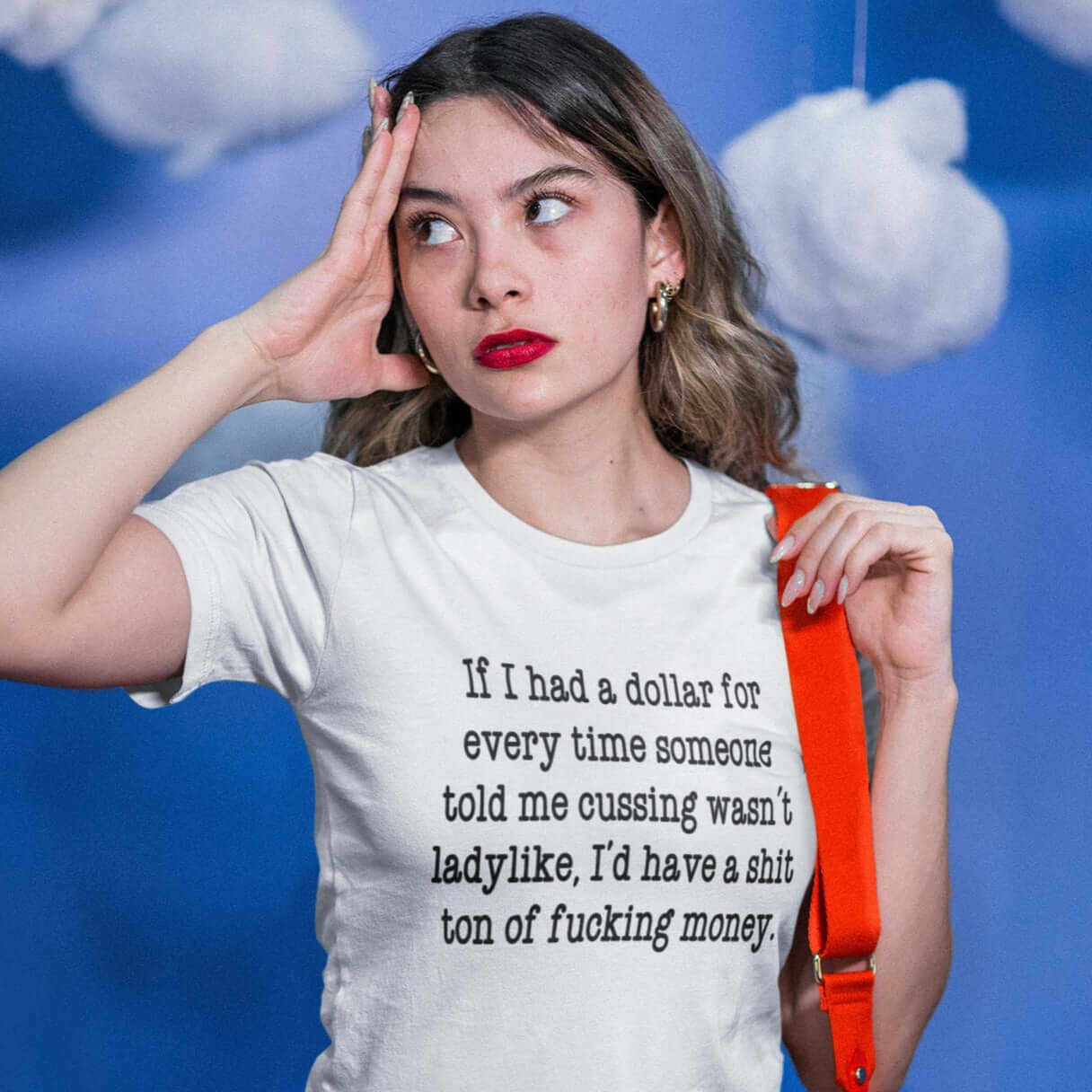 Woman wearing a white t-shirt with the phrase If I had a dollar for every time someone told me cussing wasn't ladylike I'd have a shit ton of fucking money printed on the front.