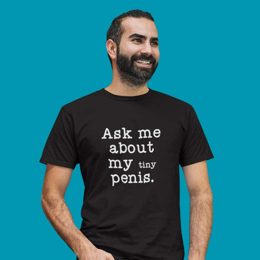 Man wearing a black t-shirt with the phrase Ask me about my tiny penis printed on the front. The word tiny is much smaller than the rest of the text.