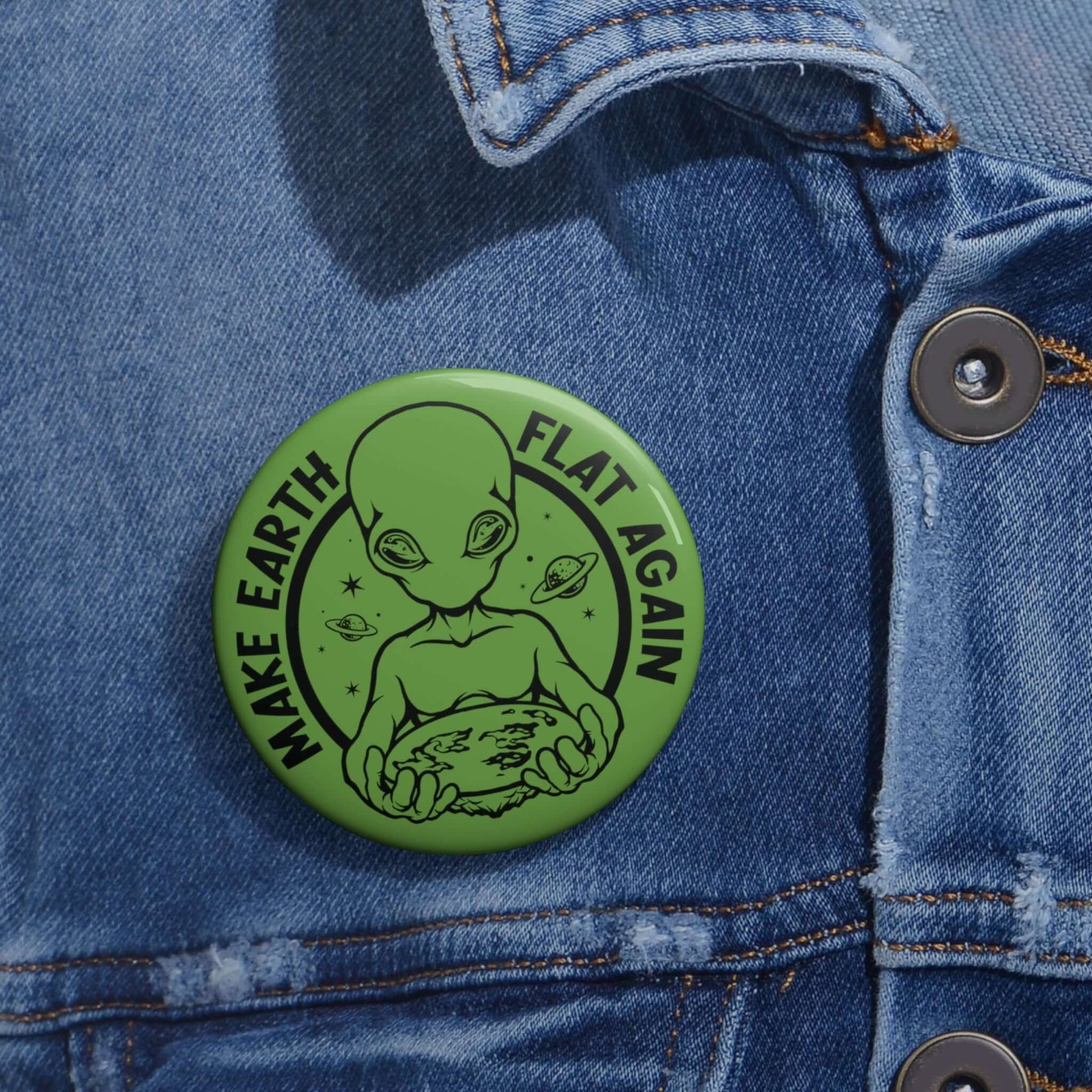 Green pinback button with an image of an alien holding flat earth and the words Make earth flat again.