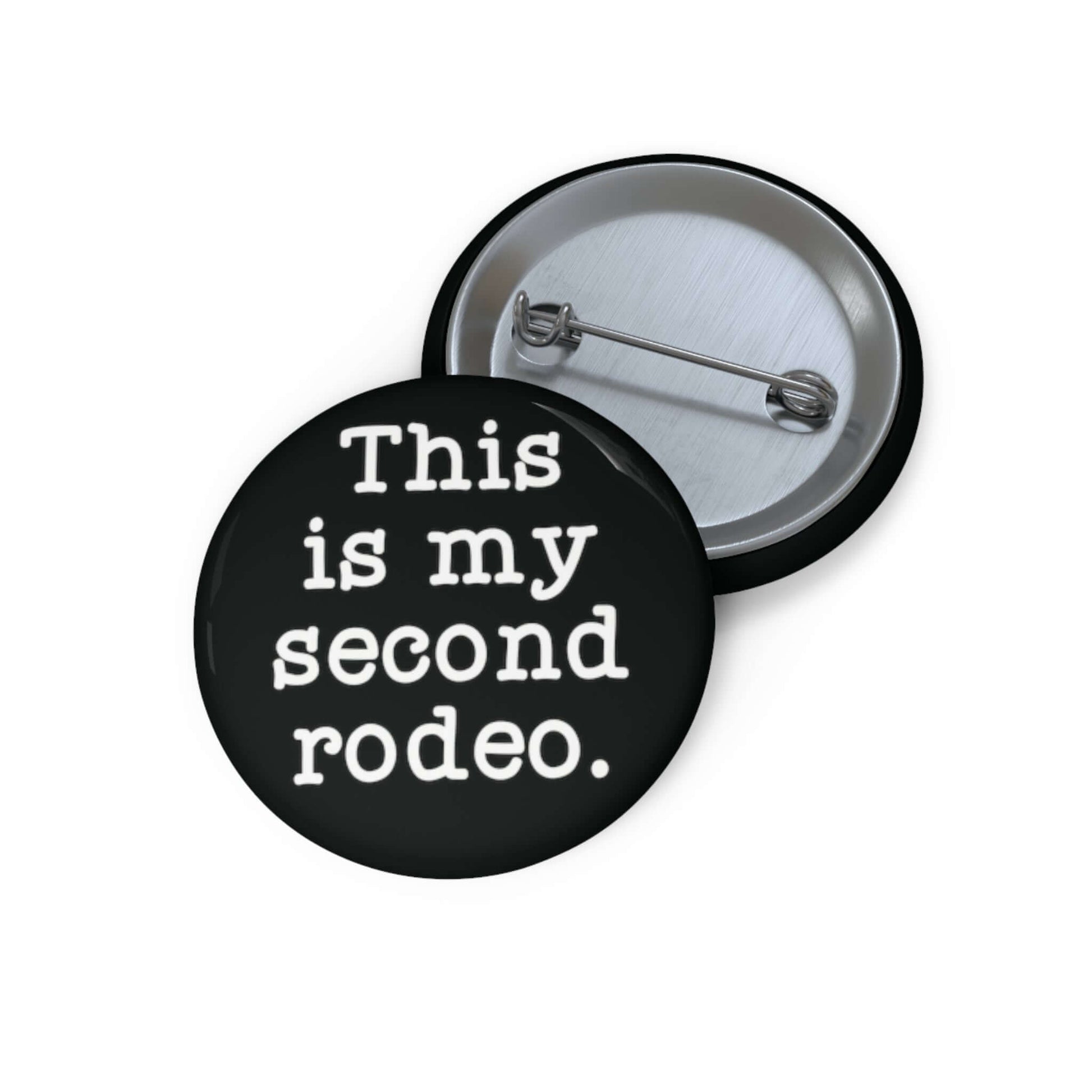 Black pin-back button with the phrase This is my second rodeo printed on it in white.