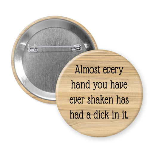 Wooden looking button with text 'Almost every hand you have ever shaken has had a dick in it.' on a white background