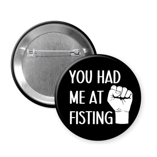 Black button badge with 'You Had Me at Fisting' text and fist graphic on a white background