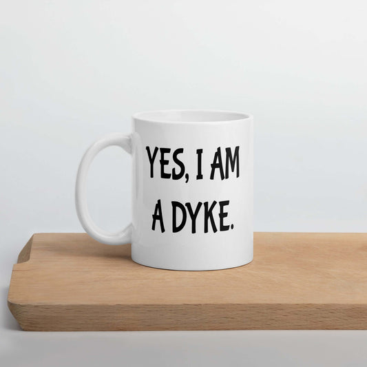 White ceramic coffee mug with the phrase Yes, I am a dyke printed on both sides.