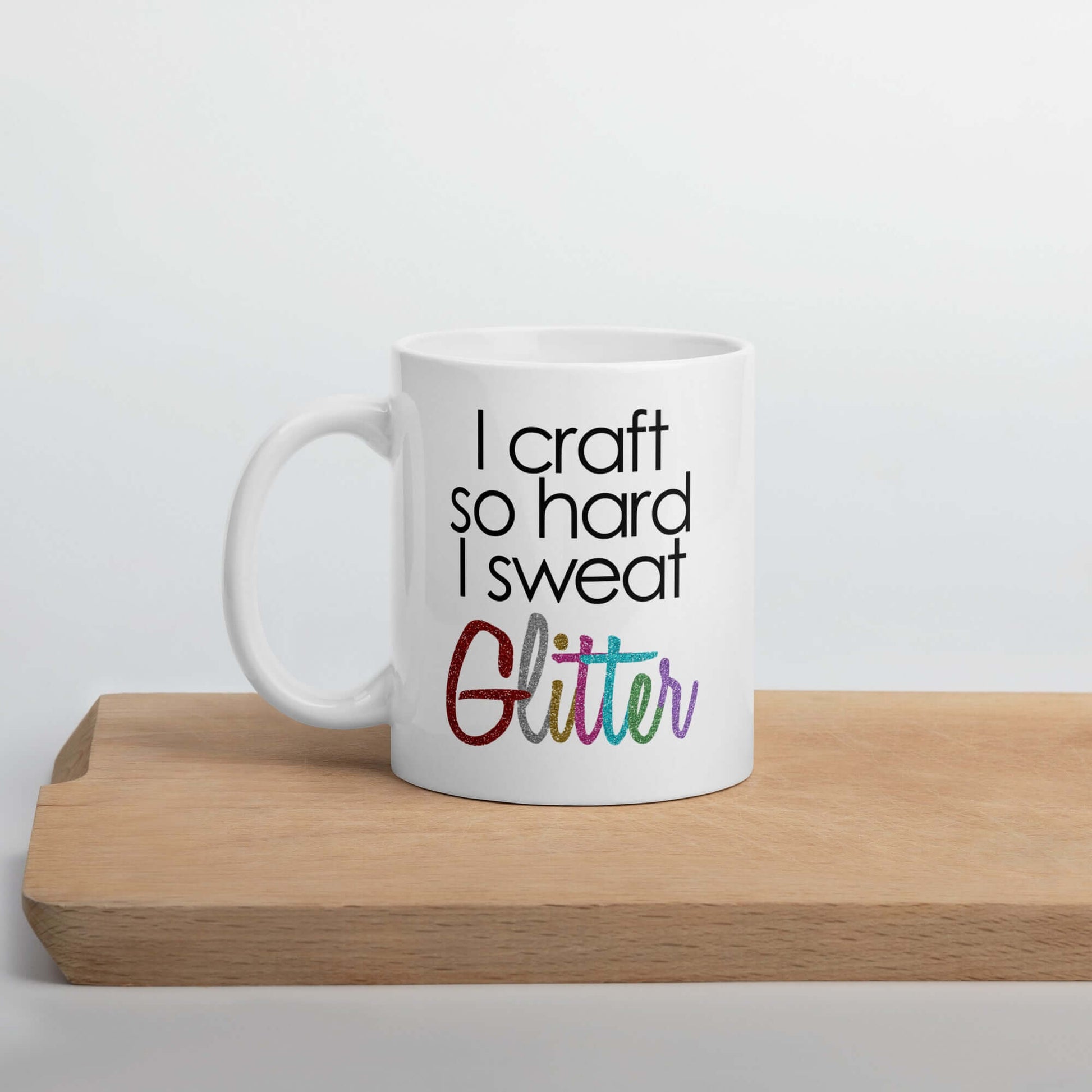 White ceramic coffee mug with the phrase I craft so hard I sweat glitter printed on both sides. The word Glitter is printed in multi colored font that looks like glitter.