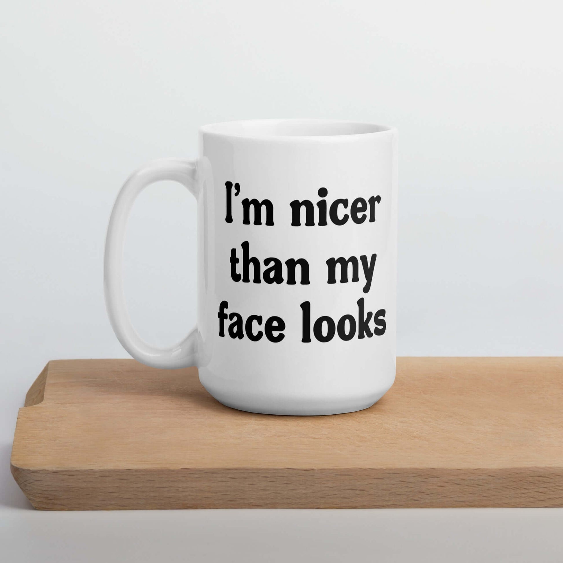 White ceramic coffee mug that says I'm nicer than my face looks printed on both sides of the mug.