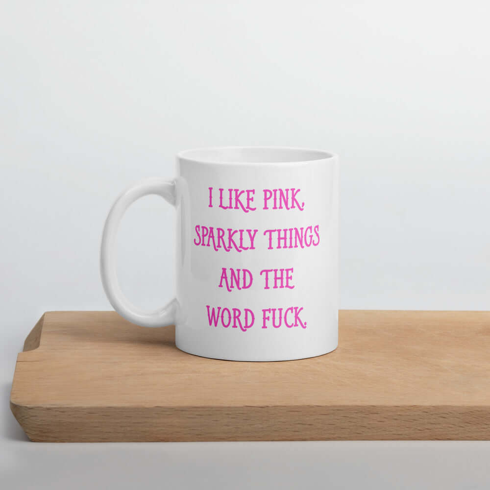 White ceramic coffee mug with the phrase I like pink, sparkly things and the word fuck printed in pink on both sides of the mug.