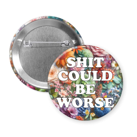 Button badge with floral design and text 'SHIT COULD BE WORSE' on a white background