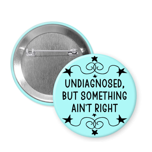 Button badge with text 'undiagnosed, but something ain't right' on a light blue background