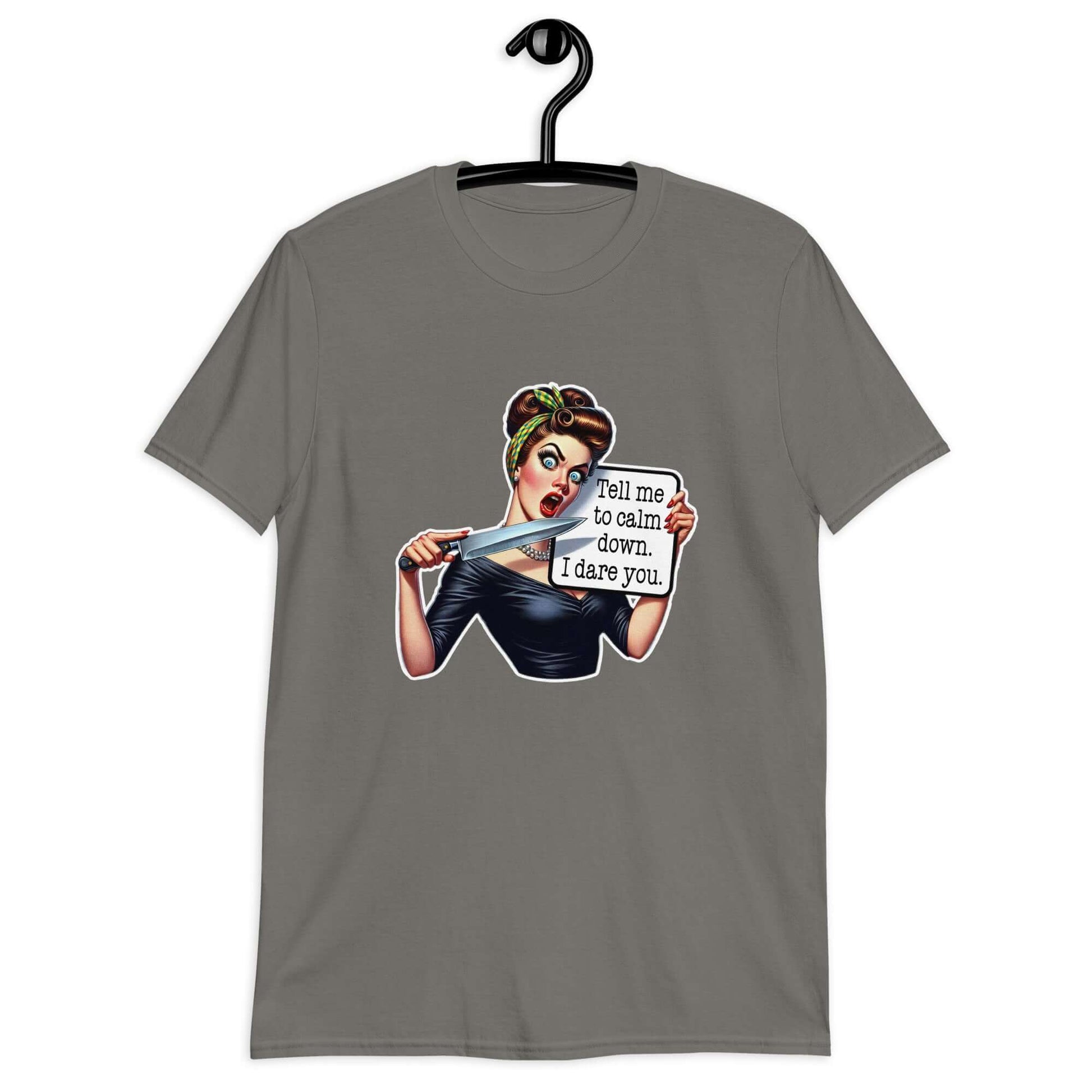 Charcoal grey t-shirt displayed on a hanger. The t-shirt has a graphic of an angry looking retro woman holding a knife and a sign. The sign says Tell me to calm down I dare you. The graphic is printed on the front of the shirt.