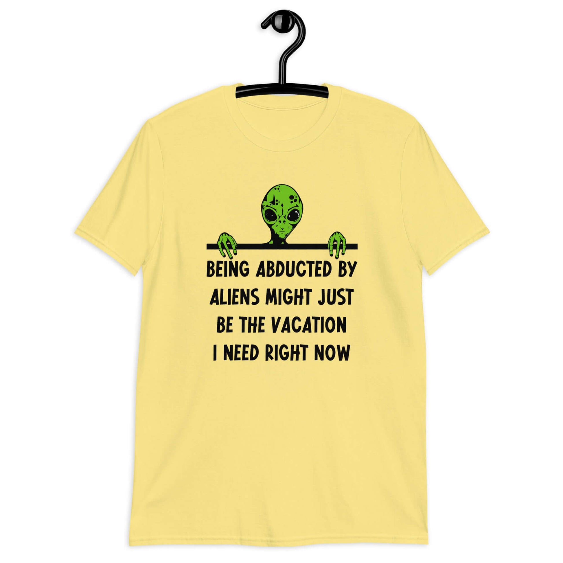 Cornsilk yellow t-shirt with an image of a green alien and the phrase Being abducted by aliens might just be the vacation I need right now printed on the front of the shirt.