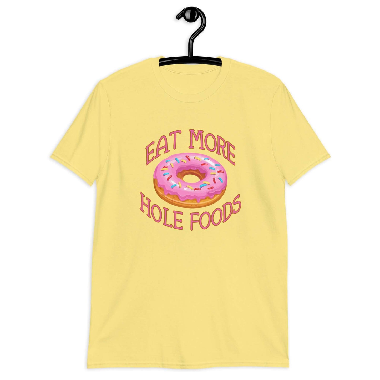 Cornsilk yellow t-shirt that has an image of a donut with pink icing and sprinkles and Eat more hole foods printed on the front.