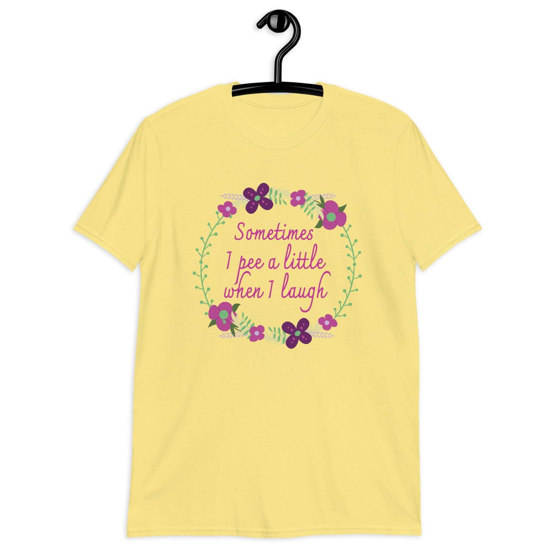 Cornsilk yellow t-shirt that has a minimalistic style line drawing floral wreath with the phrase Sometimes I pee a little when I laugh printed in the center of the wreath. The graphics are printed on the front of the shirt.