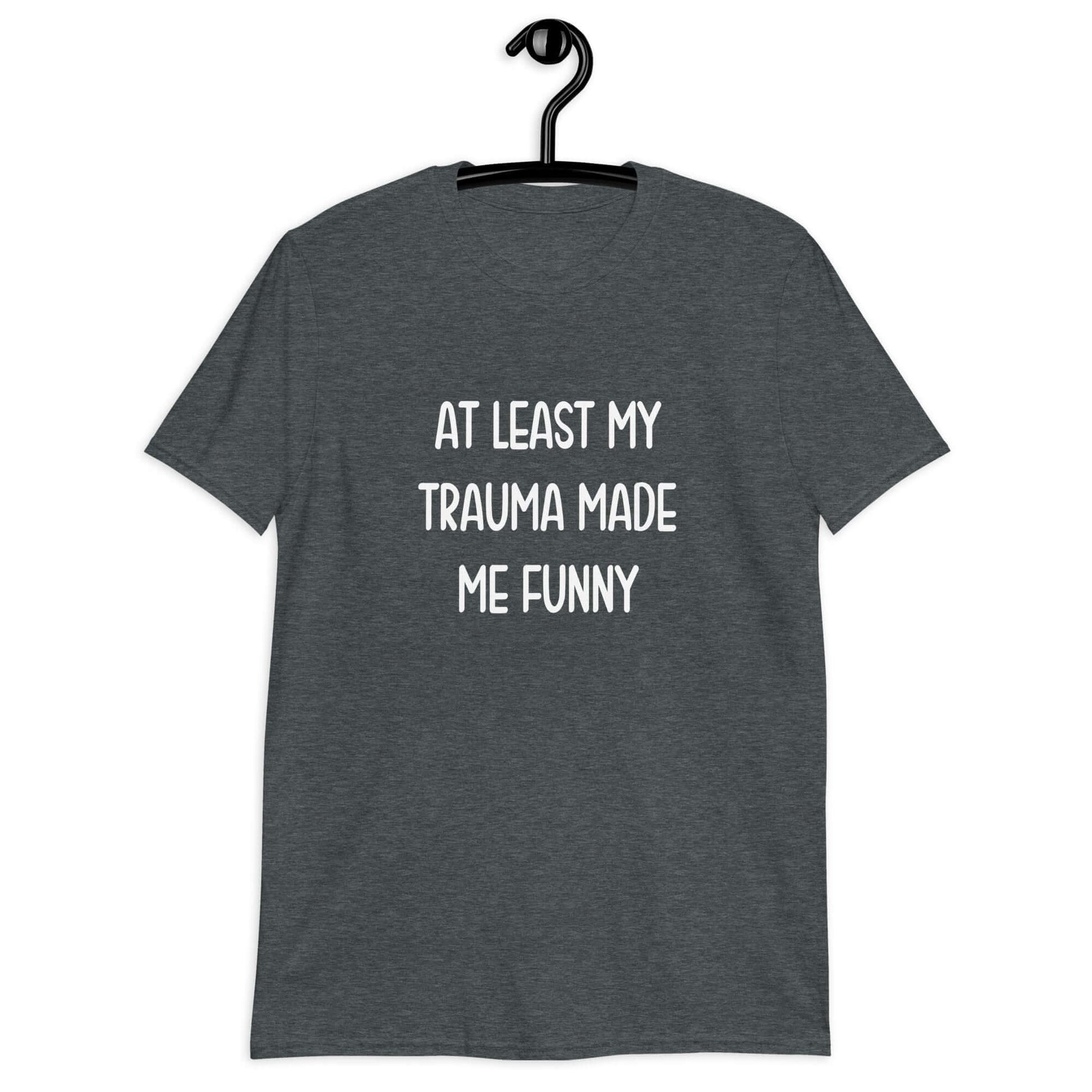 Dark heather grey t-shirt with the words At least my trauma made me funny printed on the front.