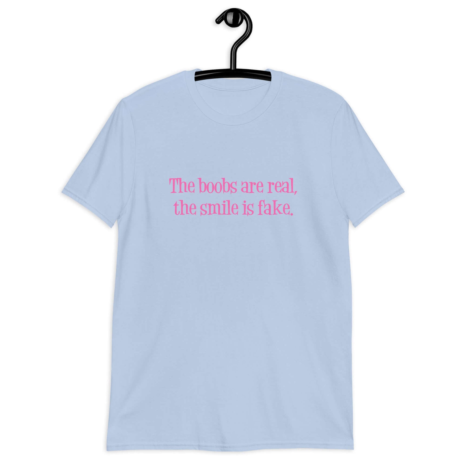 Light blue t-shirt with the phrase The boobs are real, the smile is fake printed in pink on the front.