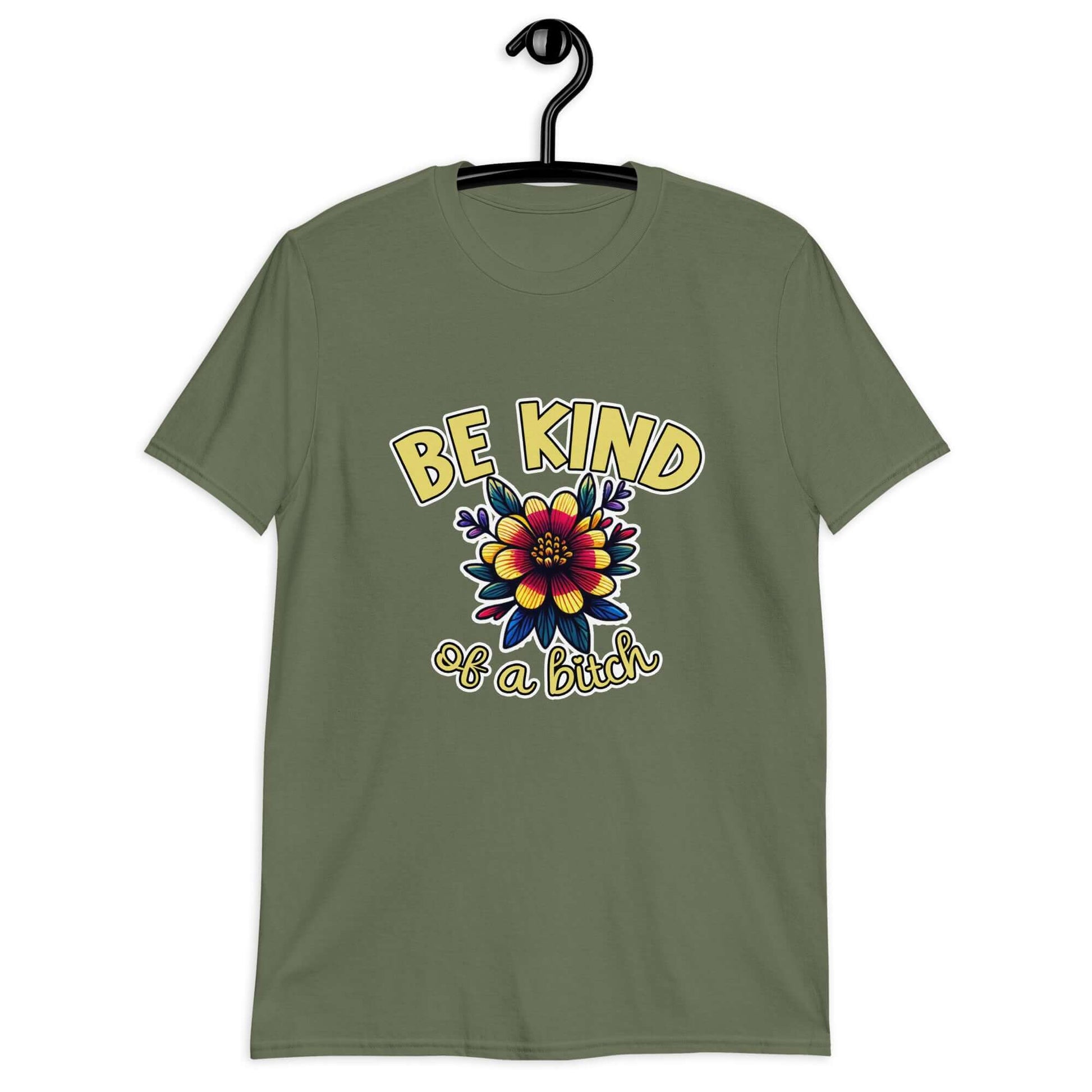 Military green t-shirt with an image of a flower and the words Be kind above the flower in yellow bold block font. The words Of a bitch are smaller in script font under the flower. The design is printed on the front of the shirt.