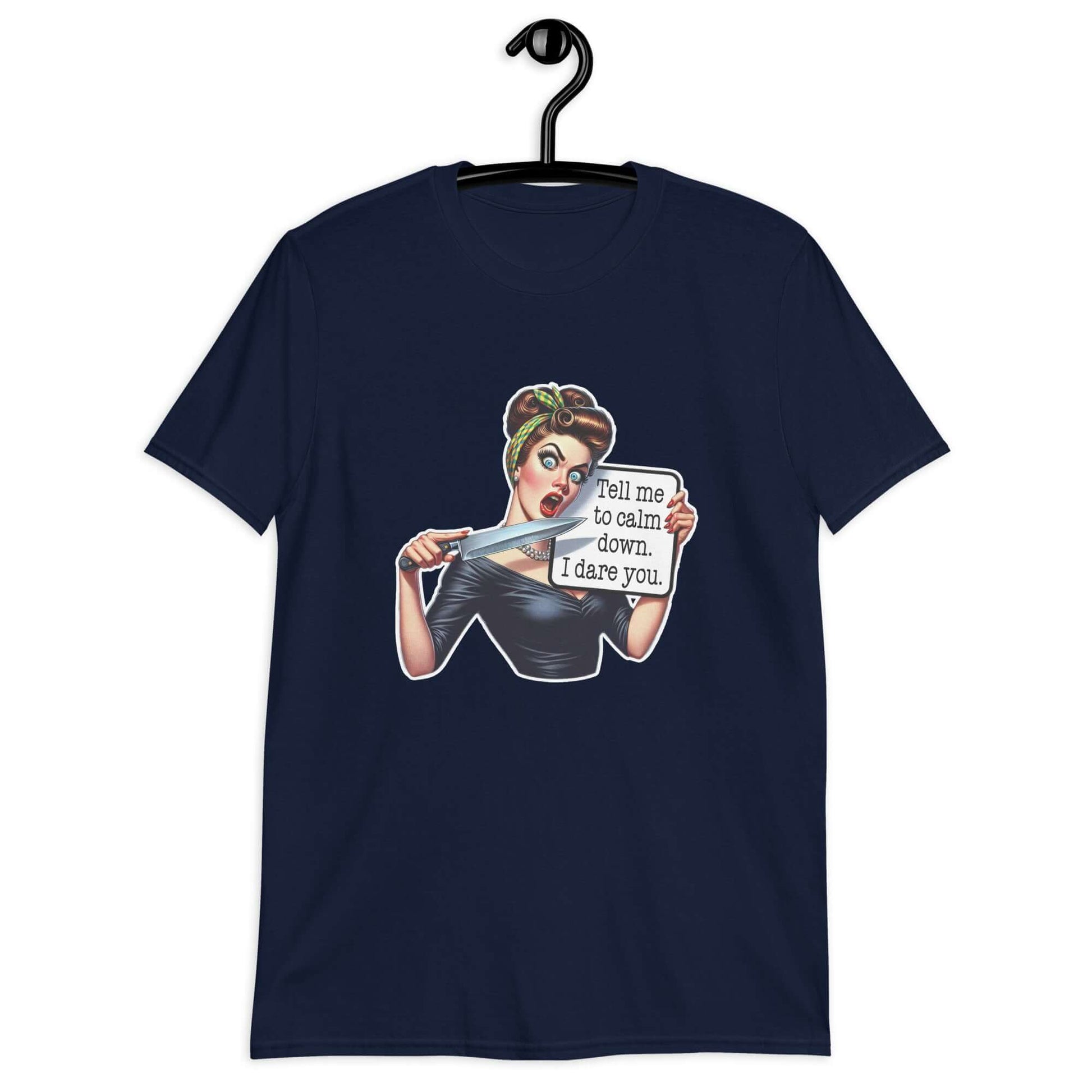 Navy blue t-shirt displayed on a hanger. The t-shirt has a graphic of an angry looking retro woman holding a knife and a sign. The sign says Tell me to calm down I dare you. The graphic is printed on the front of the shirt.