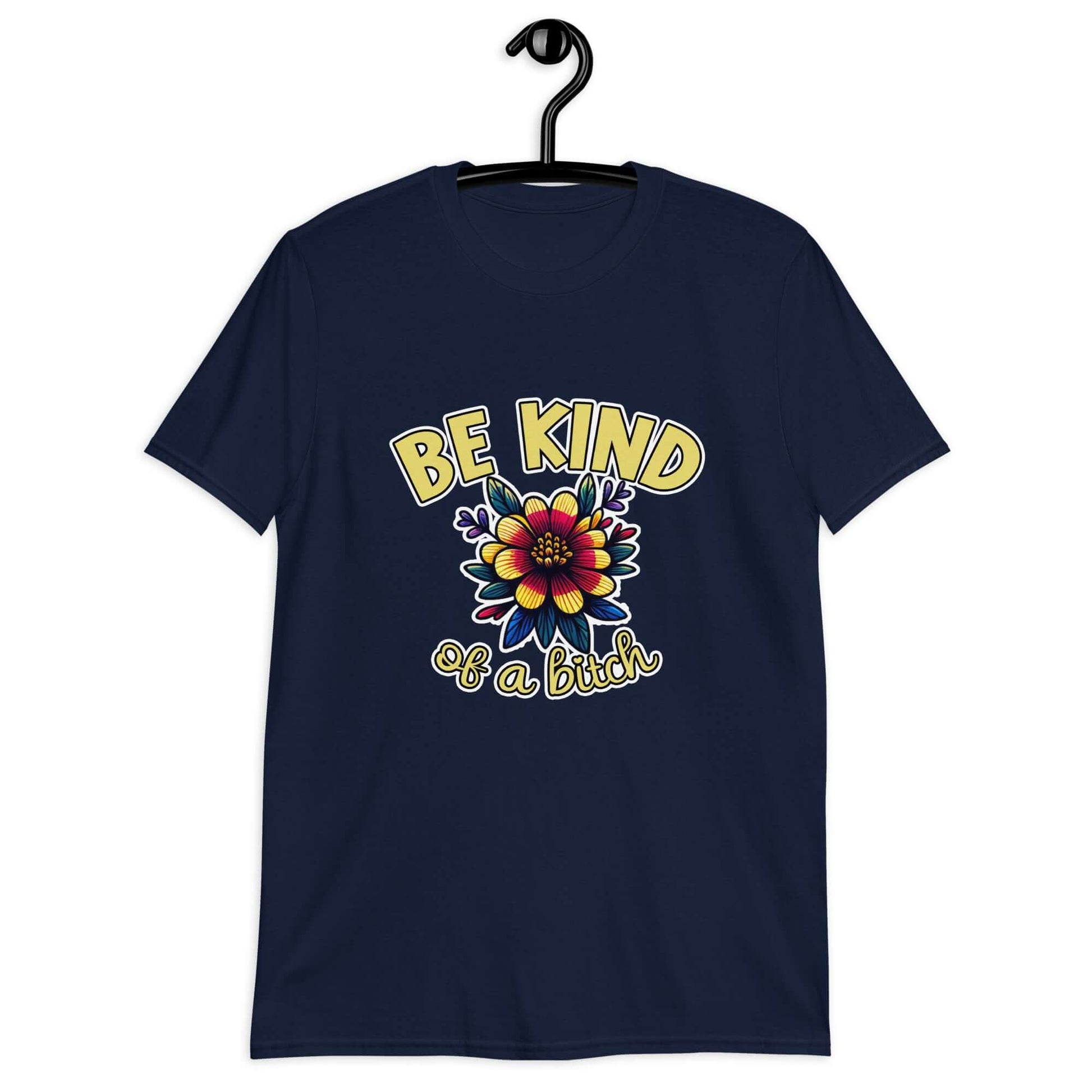 Navy blue t-shirt with an image of a flower and the words Be kind above the flower in yellow bold block font. The words Of a bitch are smaller in script font under the flower. The design is printed on the front of the shirt.