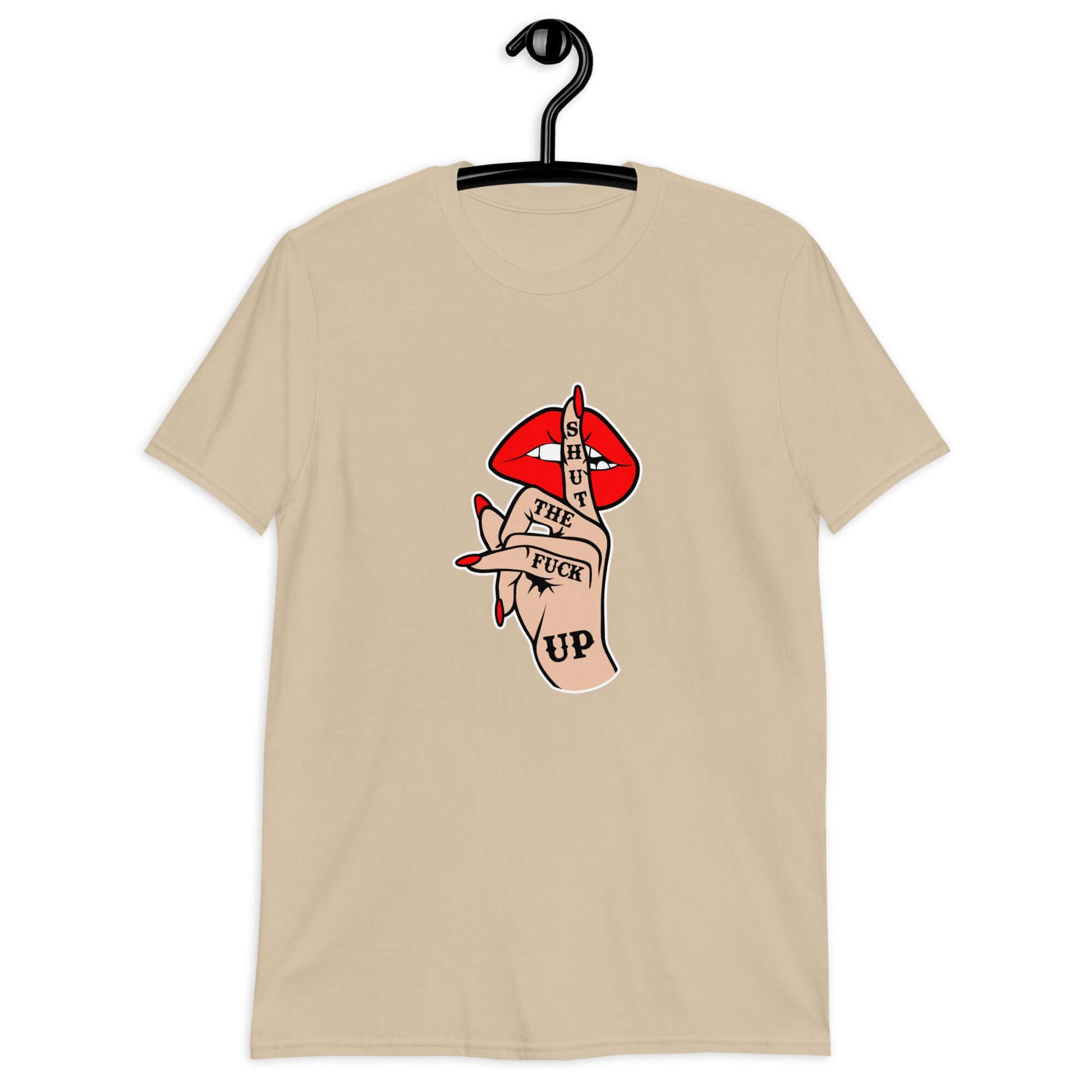 Sand color t-shirt with an image of a hand over lips making the shh gesture. The words Shut the fuck up are printed on the hand. The graphics are printed on the front of the shirt.