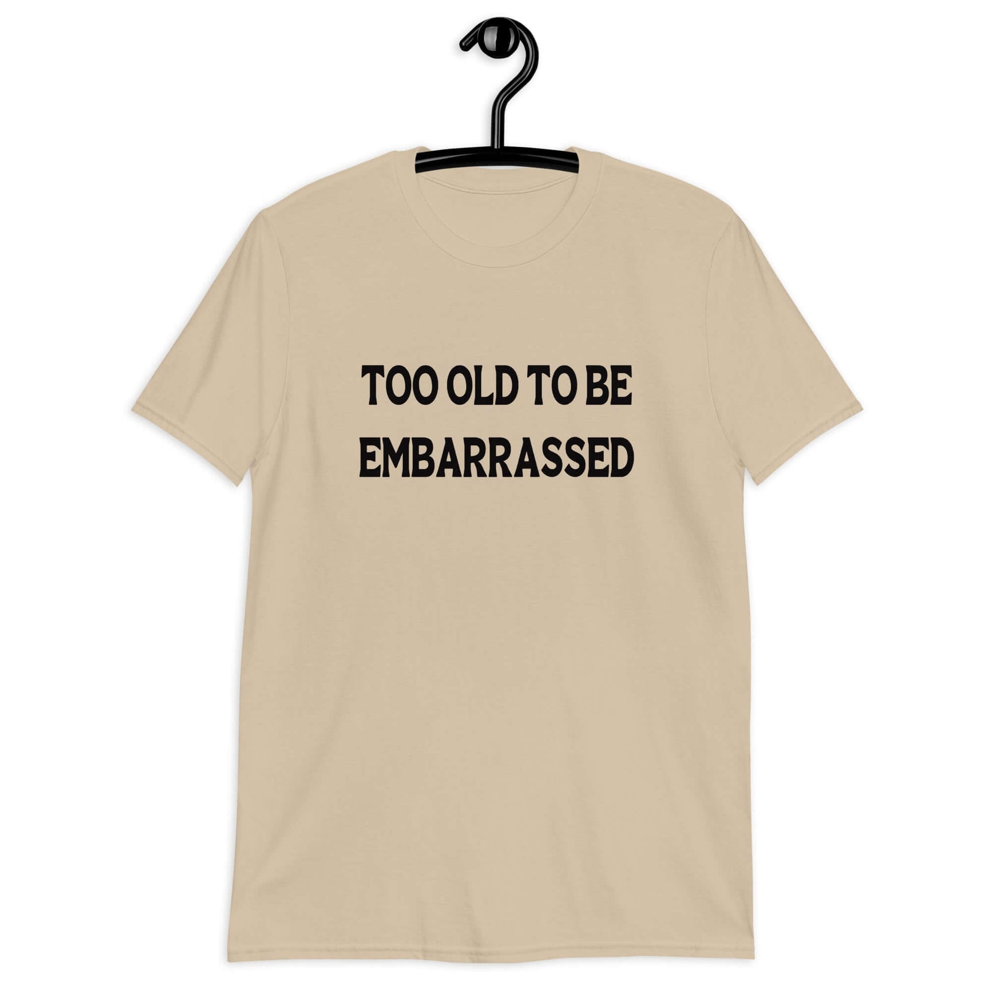 Sand t-shirt with the words Too old to be embarrassed printed on the front.