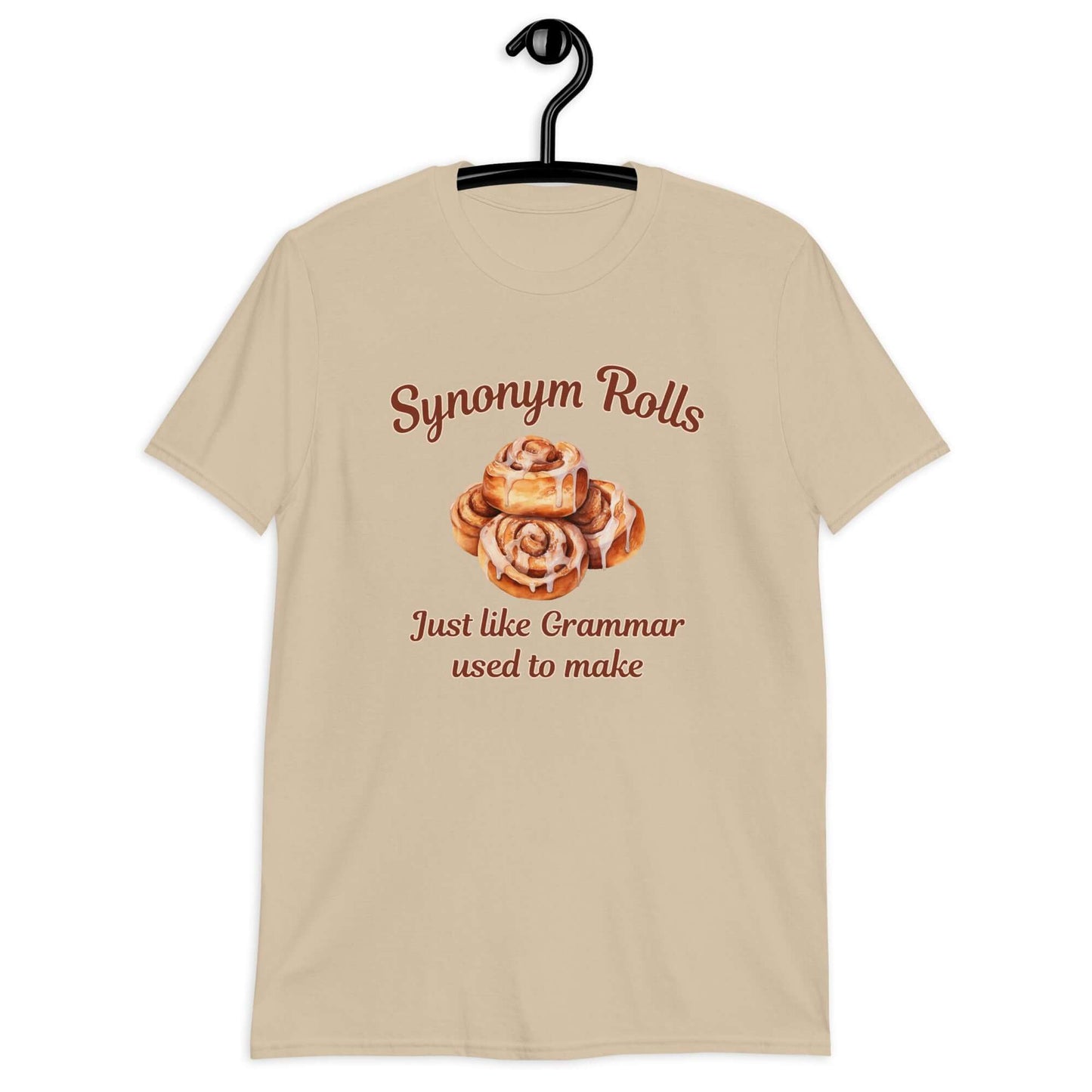 Sand color t-shirt with an image of cinnamon rolls and the pun phrase Synonym rolls Just like Grammar used to make printed on the front.