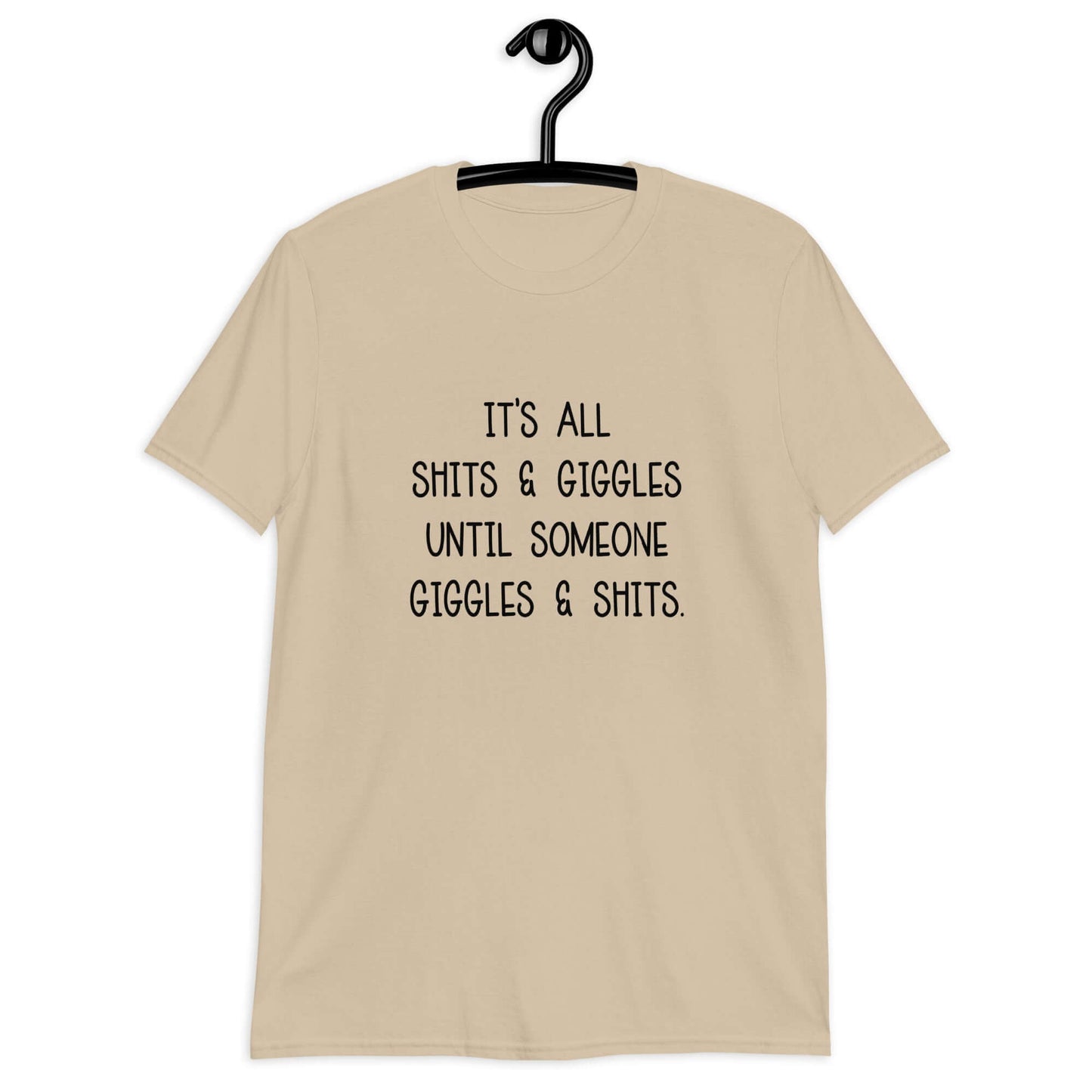 Sand color t-shirt with the phrase It's all shits & giggles until someone giggles & shits printed on the front.