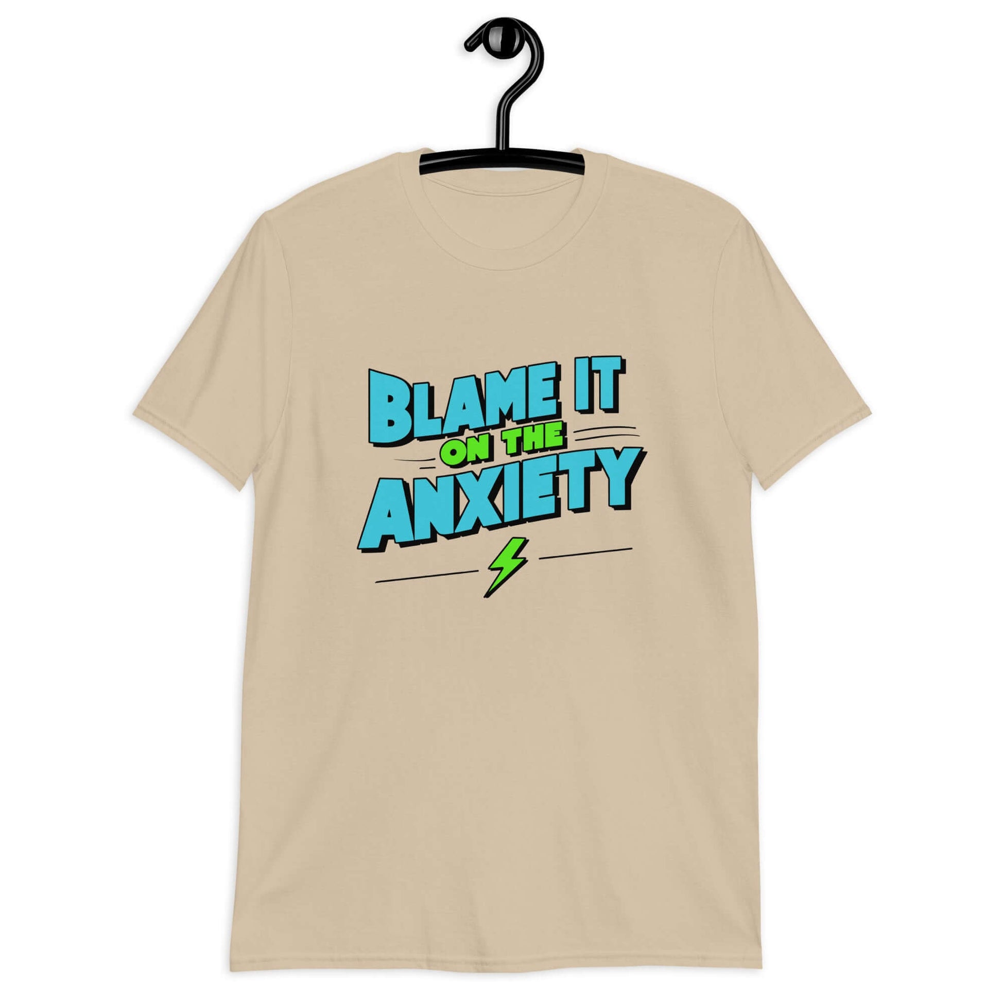 Sand color t-shirt with the phrase Blame is on the anxiety printed on the front. The graphics are bold and in aqua and lime green.