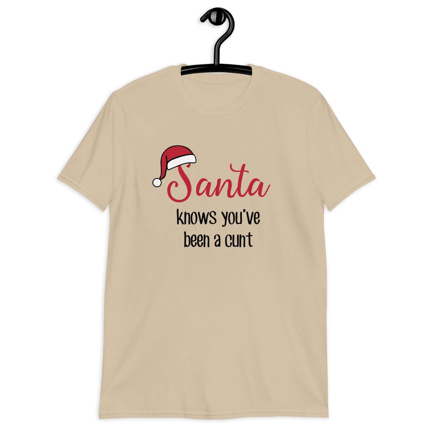 Sand color t-shirt with the words Santa knows you've been a cunt printed on the front. There is a Santa hat on the s in Santa.