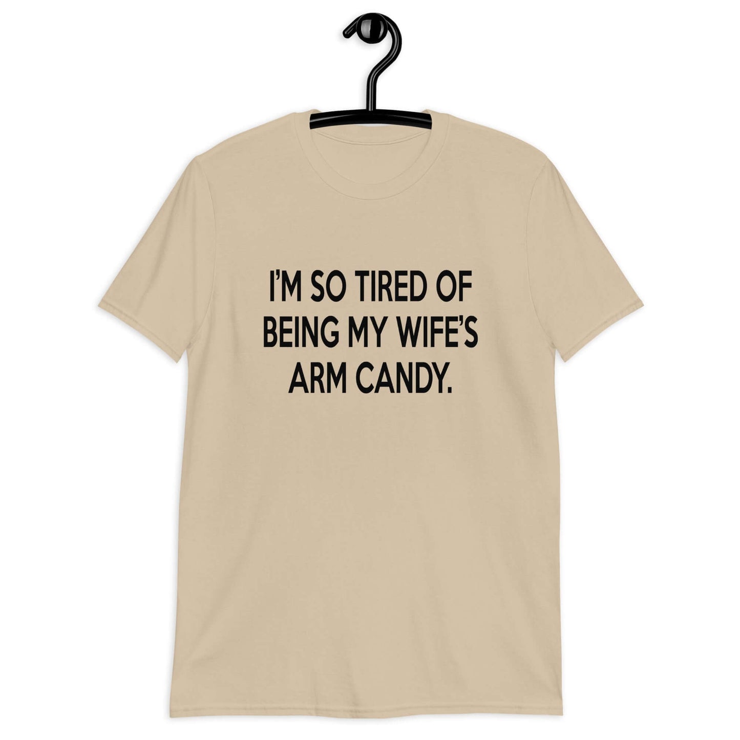 Sand color t-shirt with the funny phrase I'm so tired of being my wife's arm candy printed on the front.