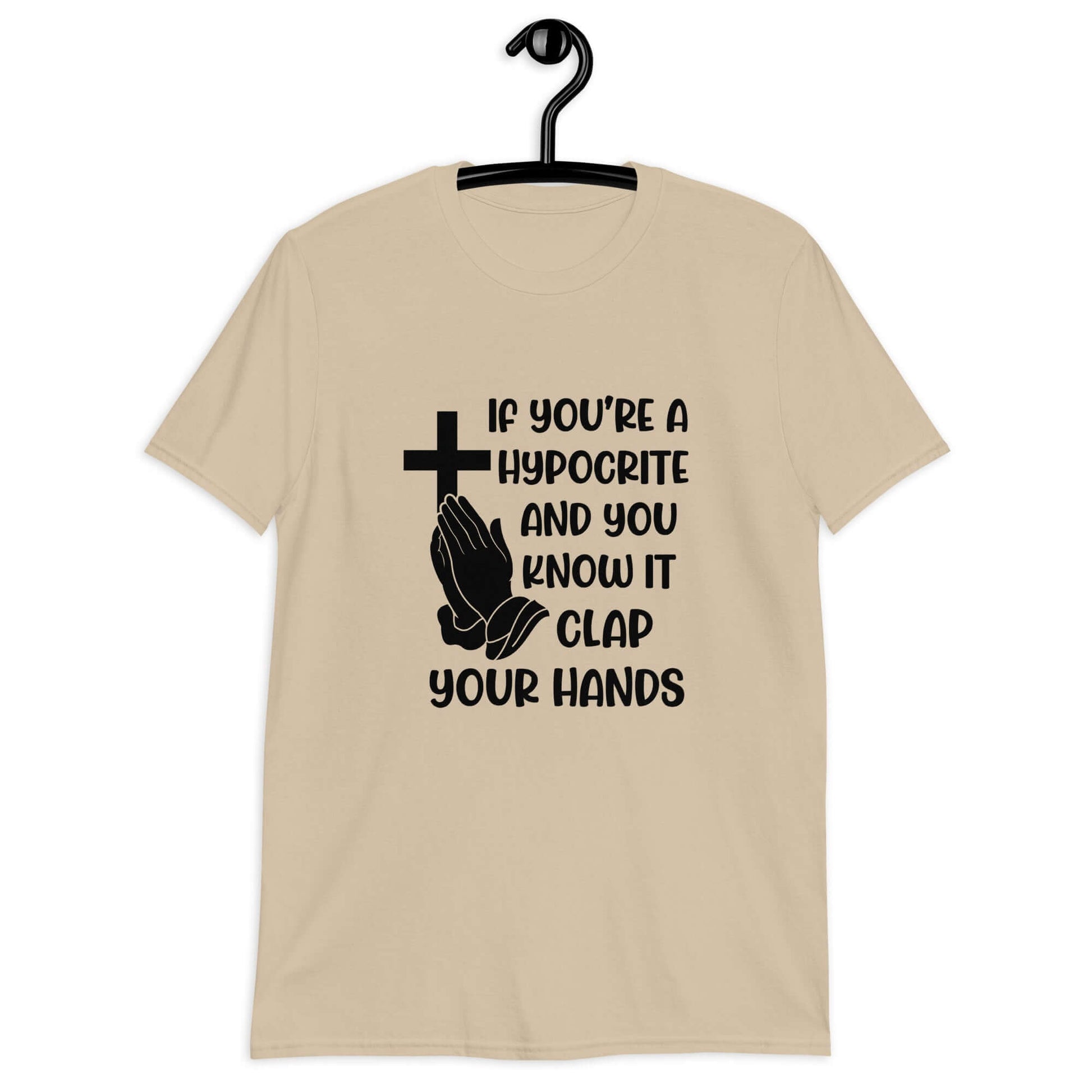 Sand color t-shirt with image of a cross and praying hands & the phrase If you're a hypocrite and you know it clap your hands printed on the front.