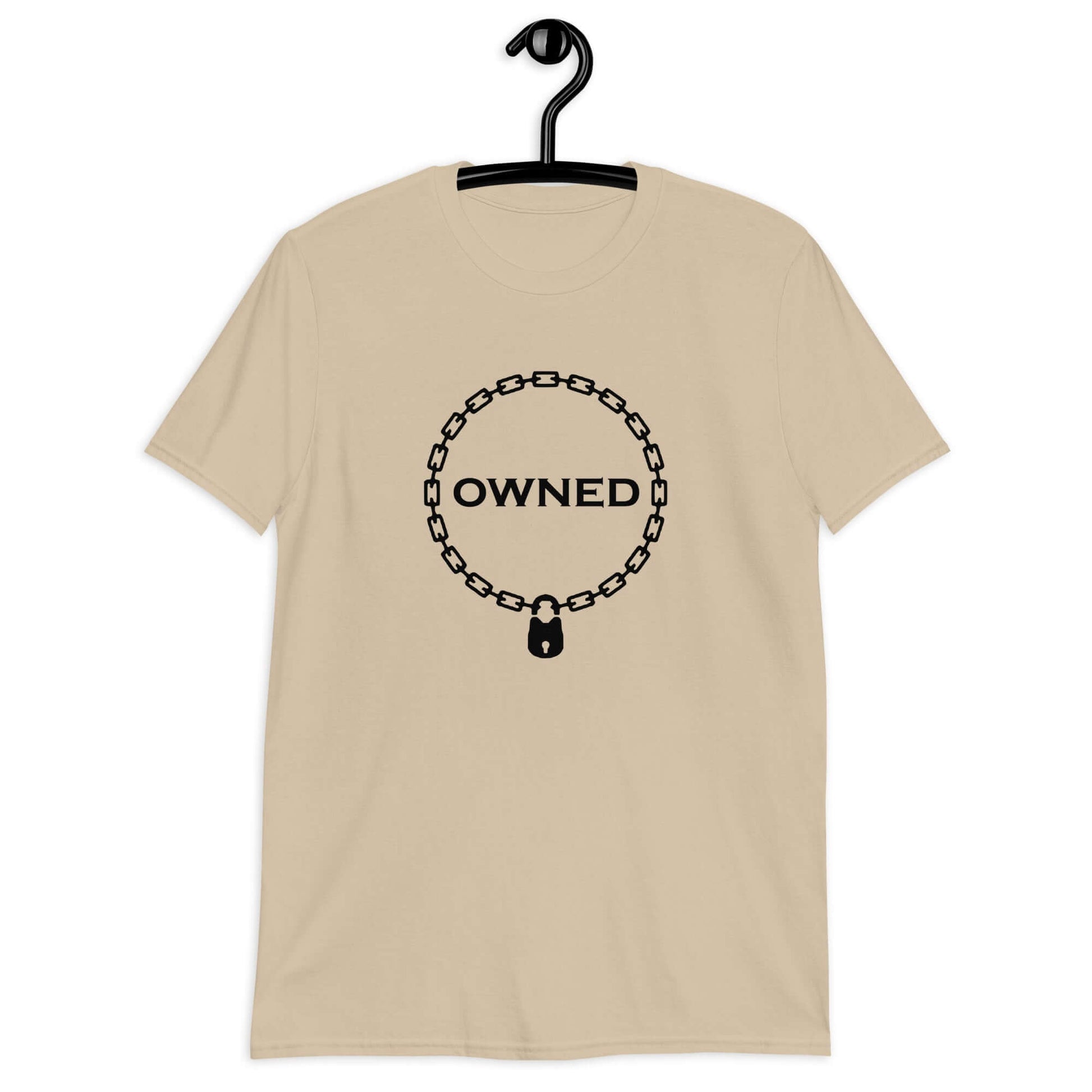 Sand t-shirt with an image of a BDSM chain collar with a lock and the word Owned printed in the center of the collar. The design is printed on the front of the shirt.