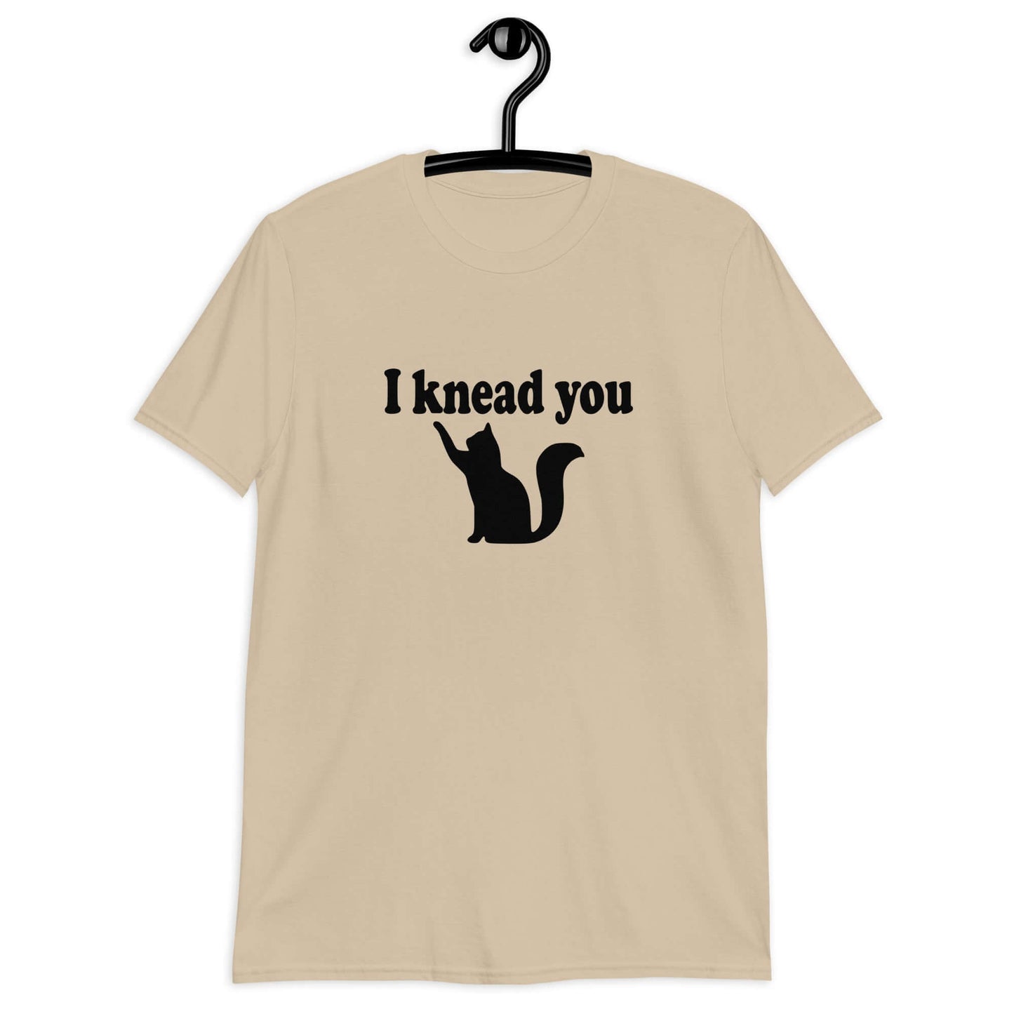 Sand color t-shirt that has an image of a silhouette of a cat and the words I knead you printed on the front.