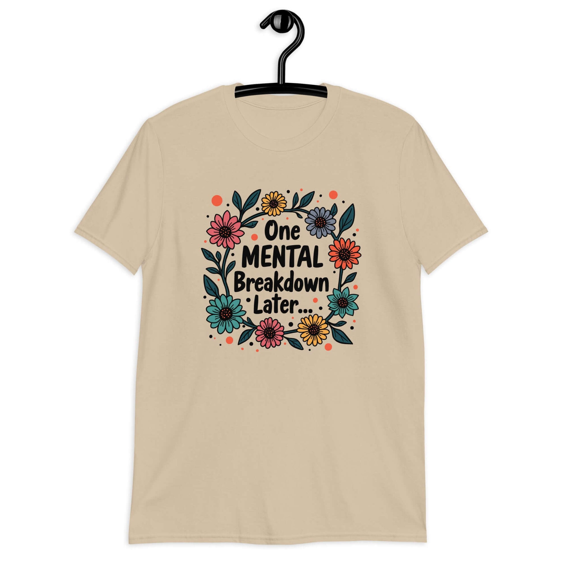 Sand color t-shirt with a multi color floral wreath design printed on the front. The words One mental breakdown later are printed in the center of the wreath. 