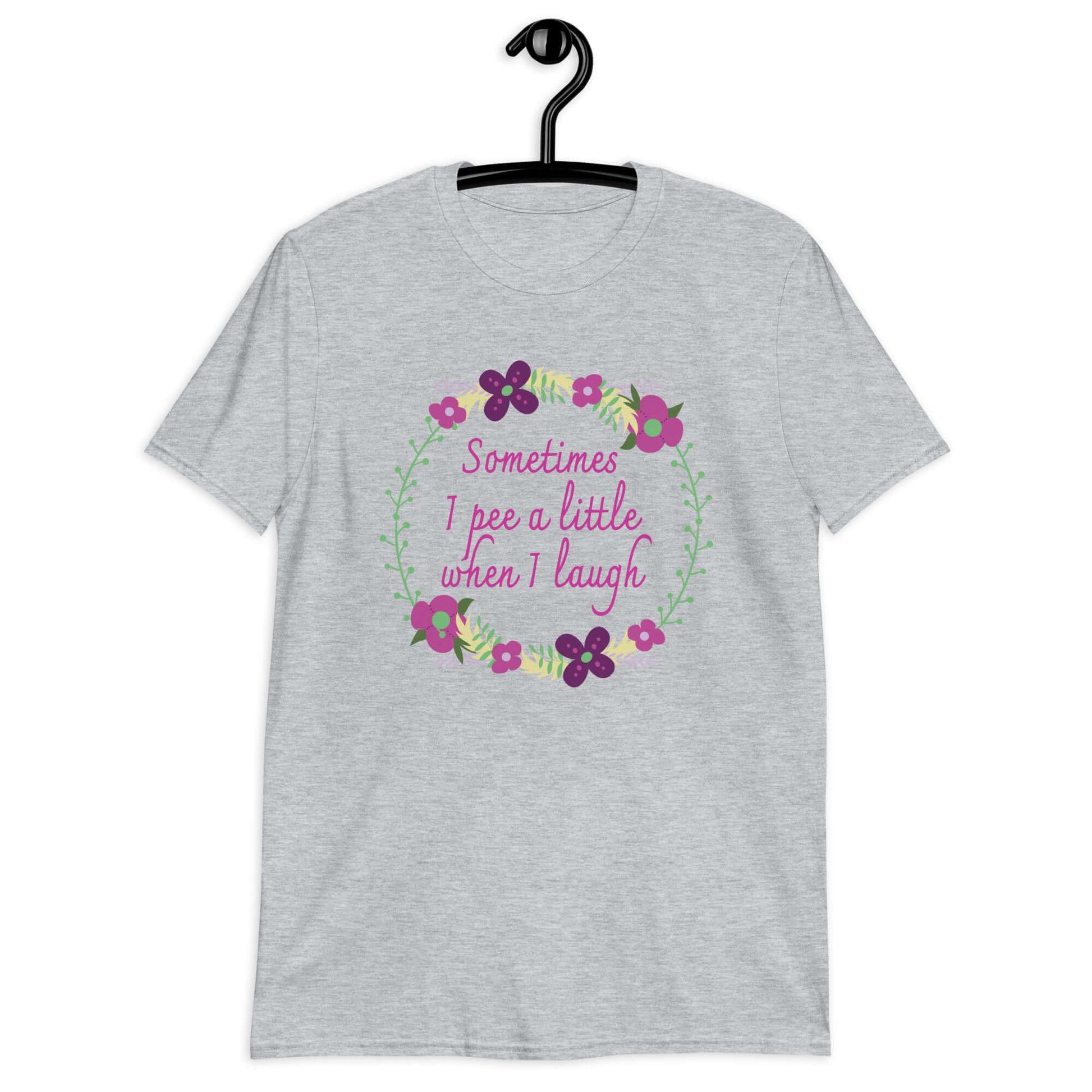 Sport grey t-shirt that has a minimalistic style line drawing floral wreath with the phrase Sometimes I pee a little when I laugh printed in the center of the wreath. The graphics are printed on the front of the shirt.