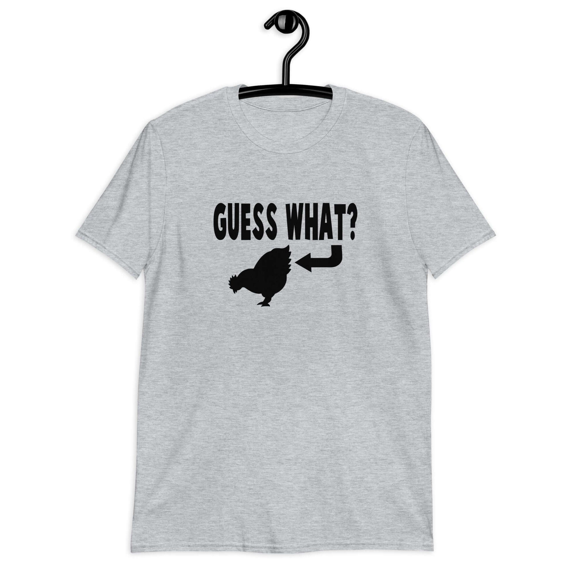 Sport grey t-shirt with an image of a chicken and the words Guess what question mark. There is an arrow pointing to the chickens butt. The graphics are printed on the front of the shirt.