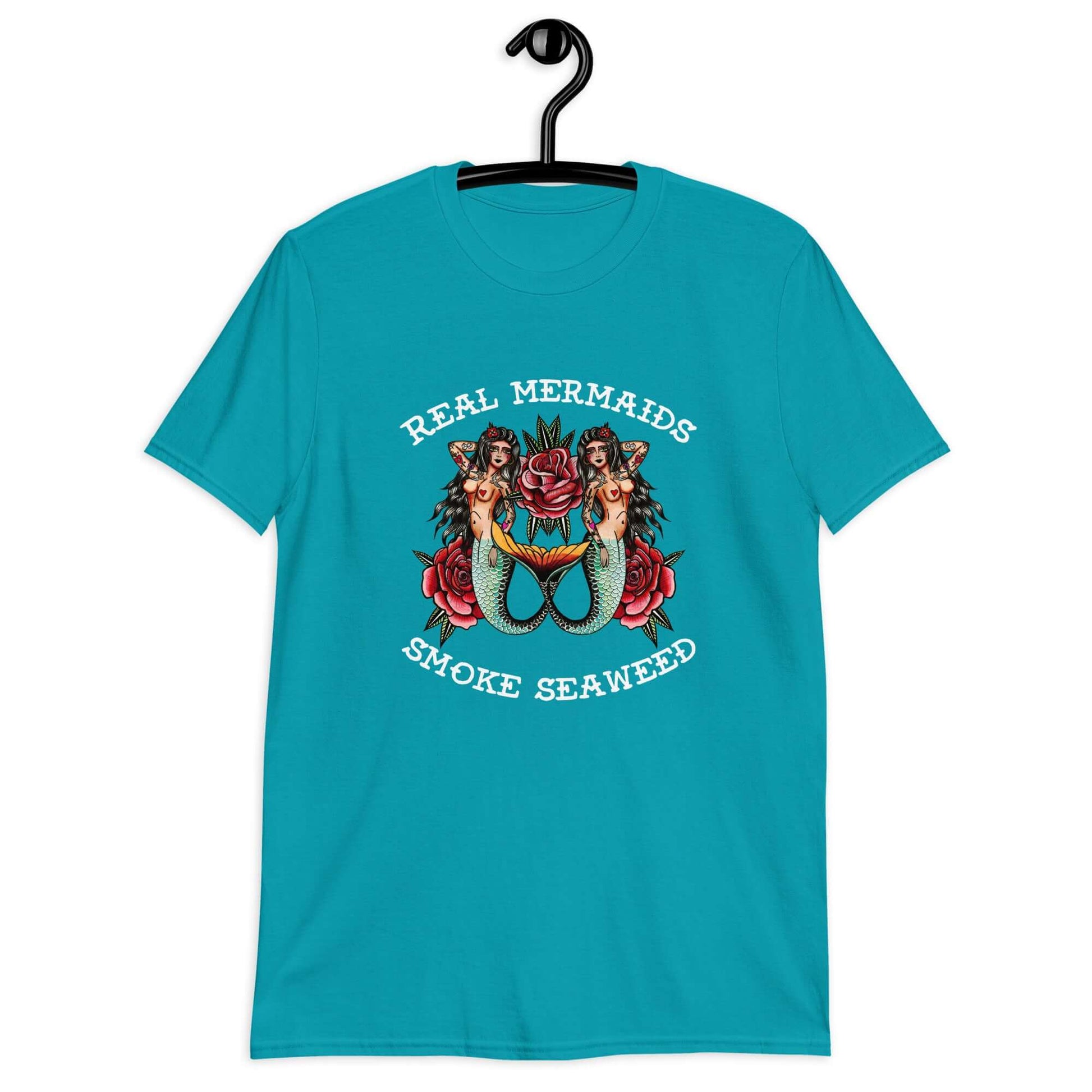 Tropical blue t-shirt with image of 2 mermaids and the words Real mermaids smoke seaweed printed on the front.