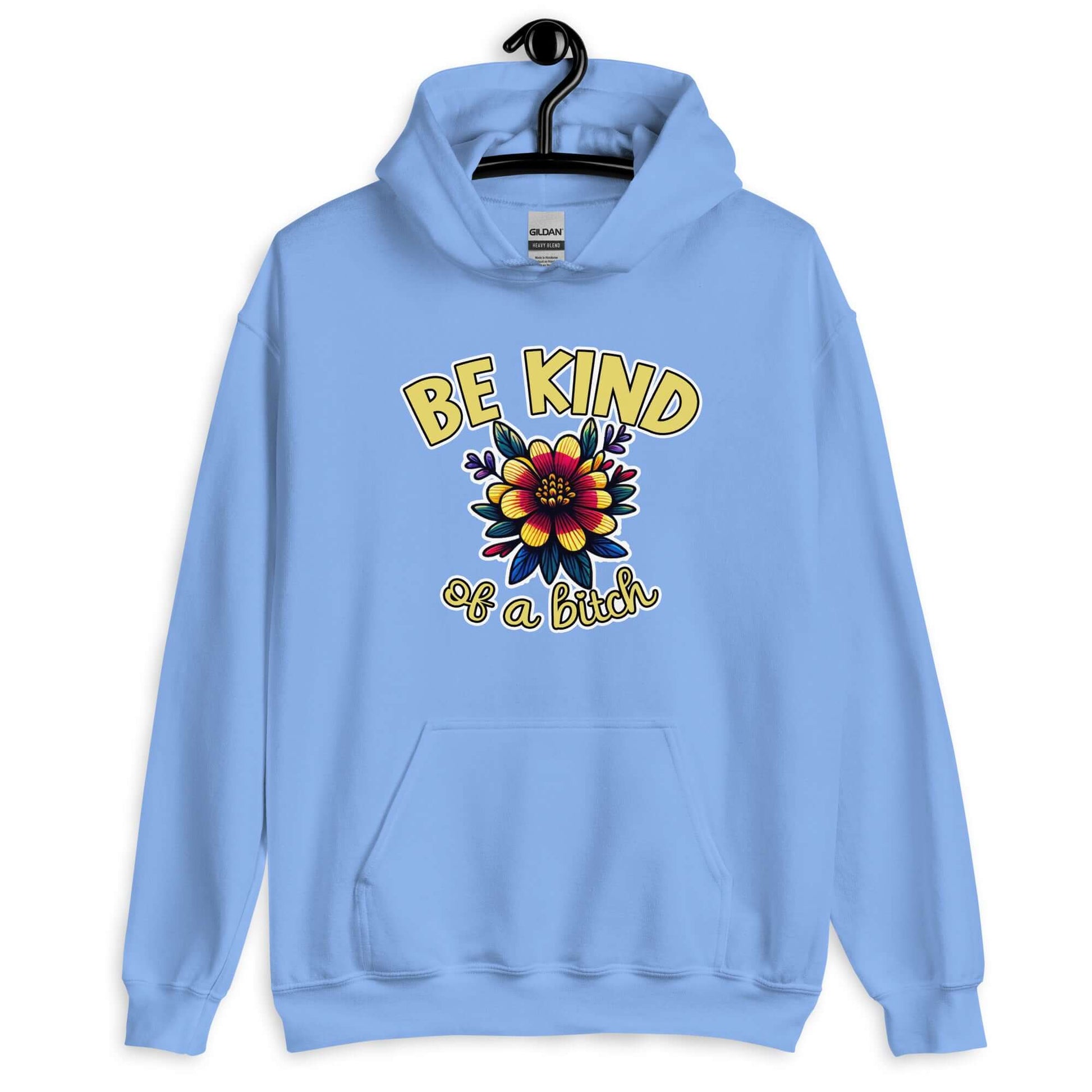 Carolina blue hoodie sweatshirt with an image of a flower and the words Be kind above the flower in yellow bold block font. The words Of a bitch are smaller in script font under the flower. The design is printed on the front of the hoodie.