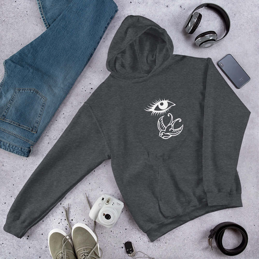 Dark heather grey hoodie sweatshirt with outline drawing of an eye and a swallow bird printed on the front.